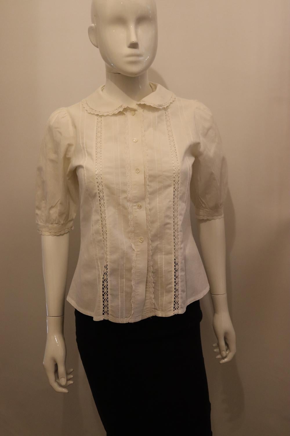 A pretty white vintage cotton blouse, perfect for Spring / Summer. In a heavy cotton , the blouse has a peter pan collar with lace trim and puff sleaves with pin tuck detail. It has a button front opening with lace and pin tuck detail.