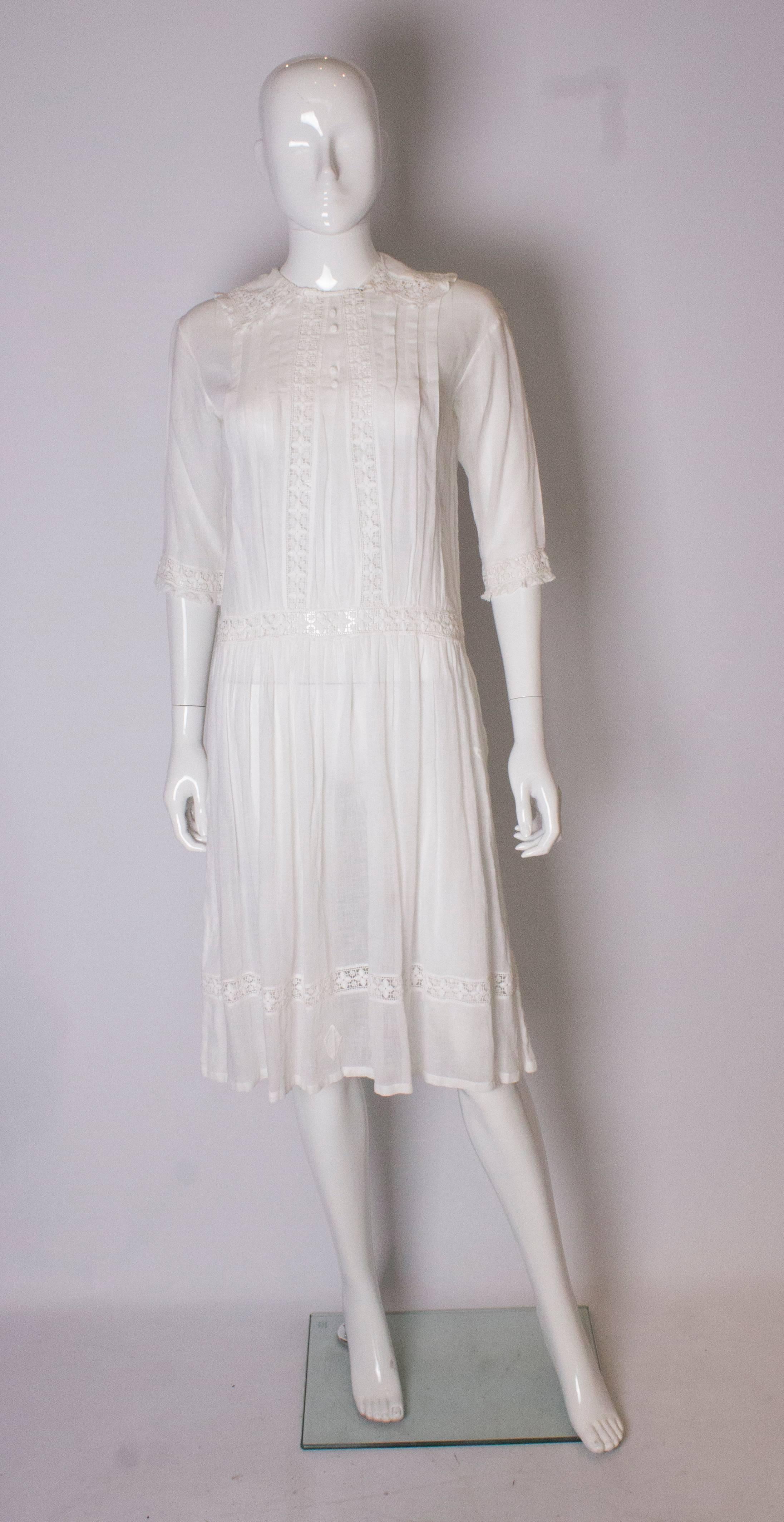 A pretty vintage edwardian white cotton dress . The dress has lace detail on the the cuffs and collar, with pleats on the front.  It has elbow length sleeves with lace detail.