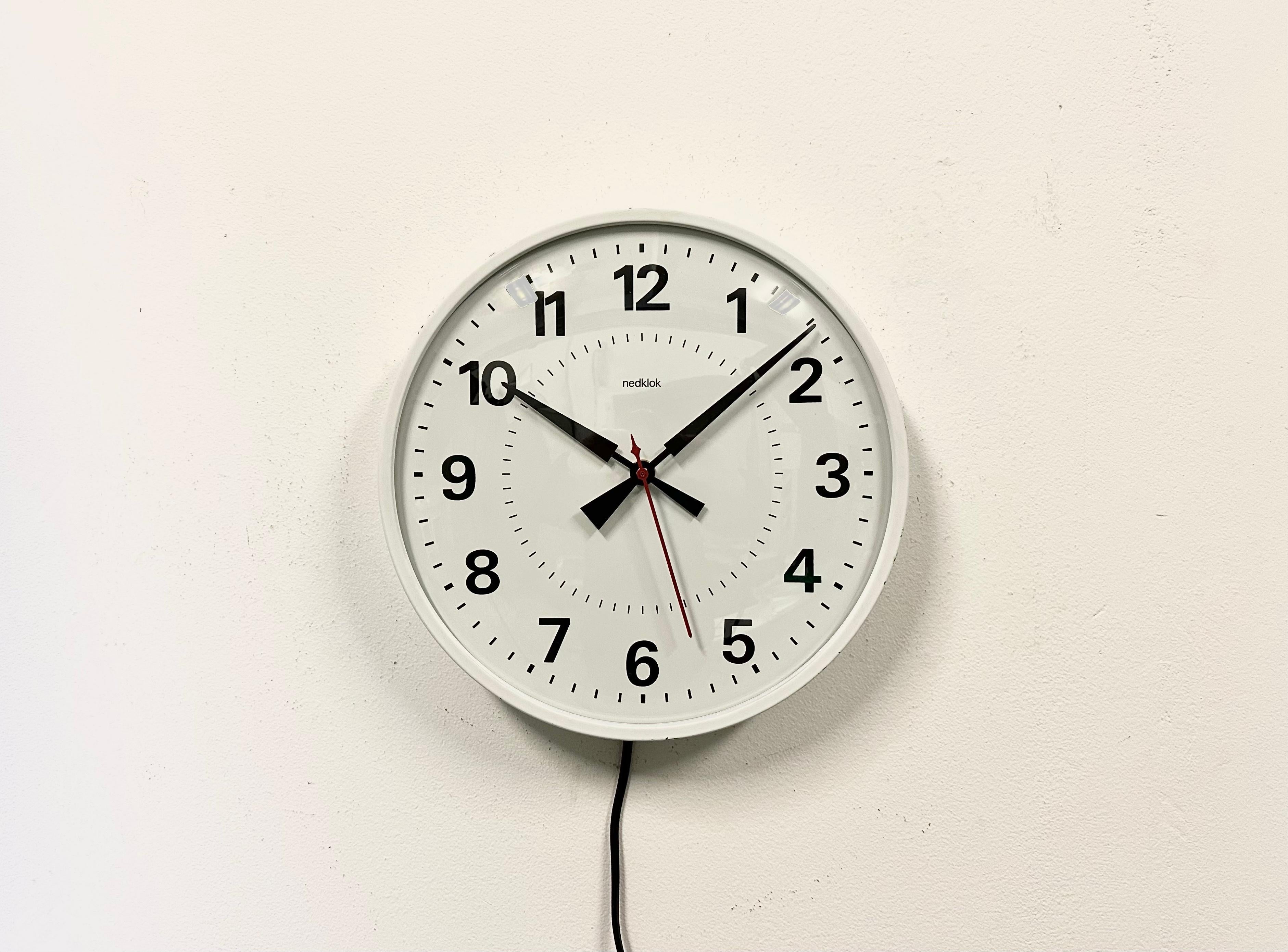 Nedklok wall clock was made in Netherlands during the 1970s. It features a white iron frame, a metal dial, an aluminium hands, and convex clear glass cover. Original electric movement ( 220 V ) works perfectly . The diameter of the clock is 28
