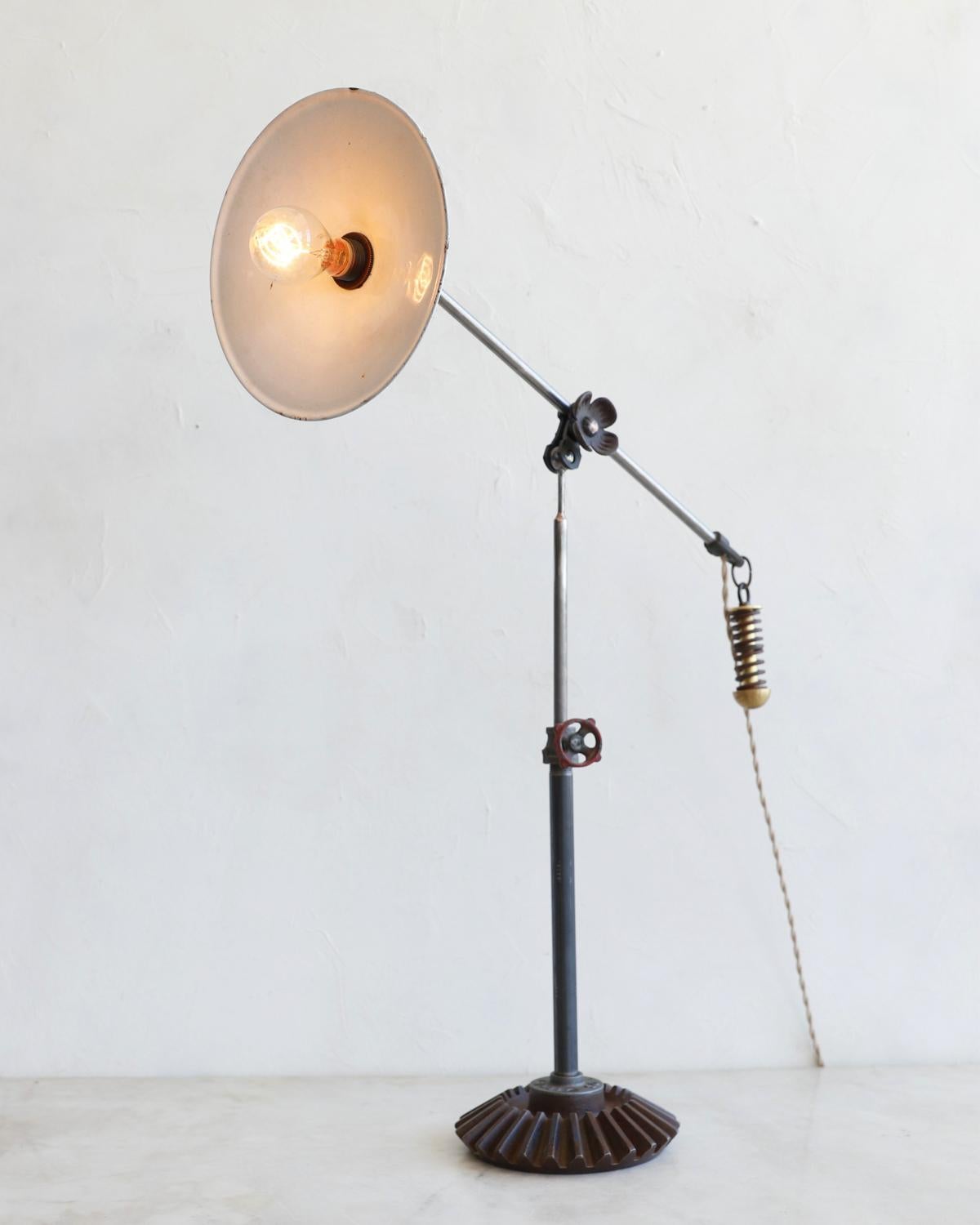 Robert True Ogden's one-of-a-like found object lamps are made by hand in Philadelphia. Crafted from pieces and parts sourced locally and abroad, no two lamps are alike. This table lamp has a vintage enamel shade, vintage gears that lock the