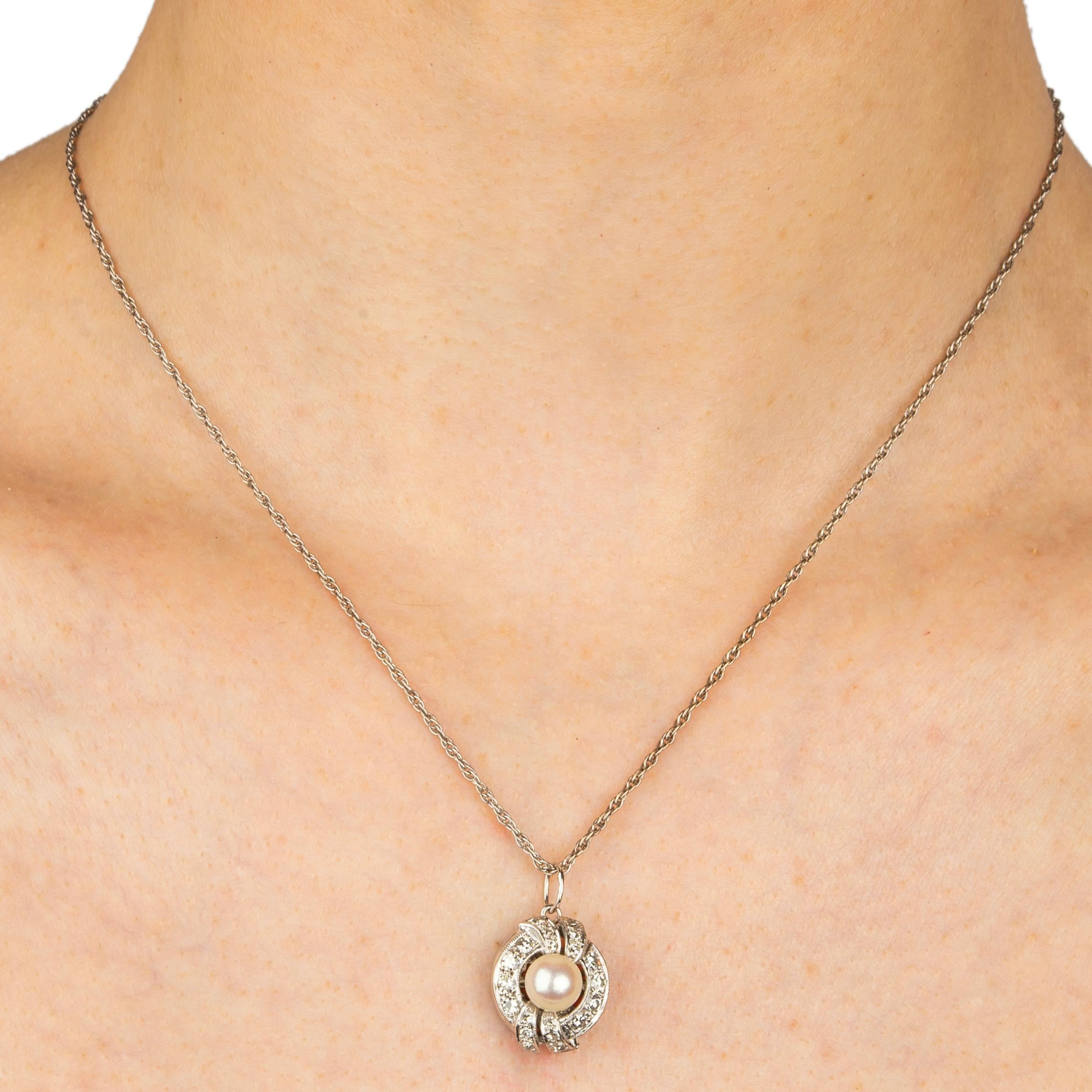 Beautiful cultured pearl and diamond pendant enhanced with scrolls on the top and bottom mounted in 14k white gold. The front is set with a lustrous pearl measuring approximately 6.4mm diam., surrounded by 20 round bright near colorless single cut