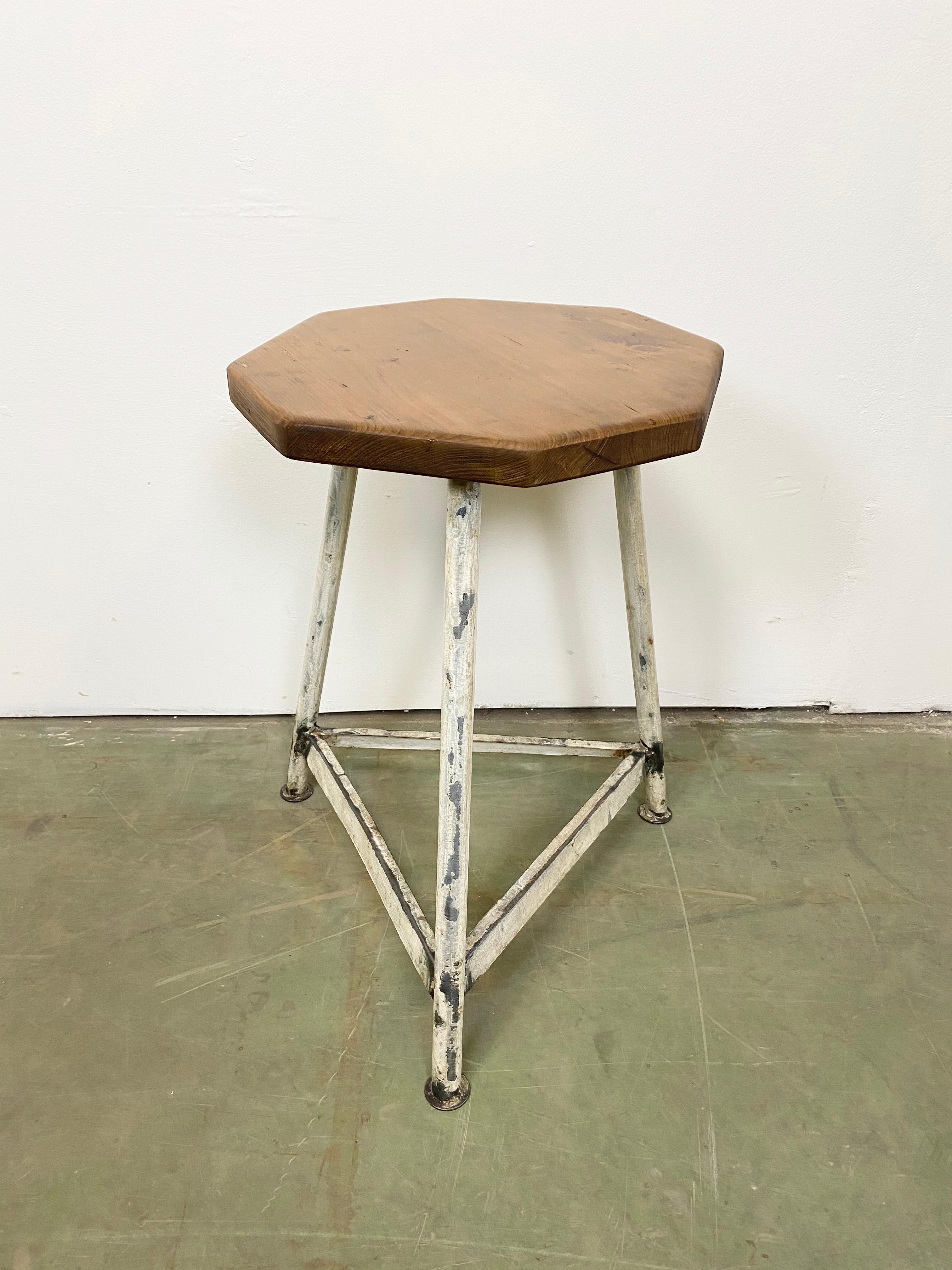 Industrial stool with a wooden seat and white metal frame. The weight of the stool is 3,5 kg.