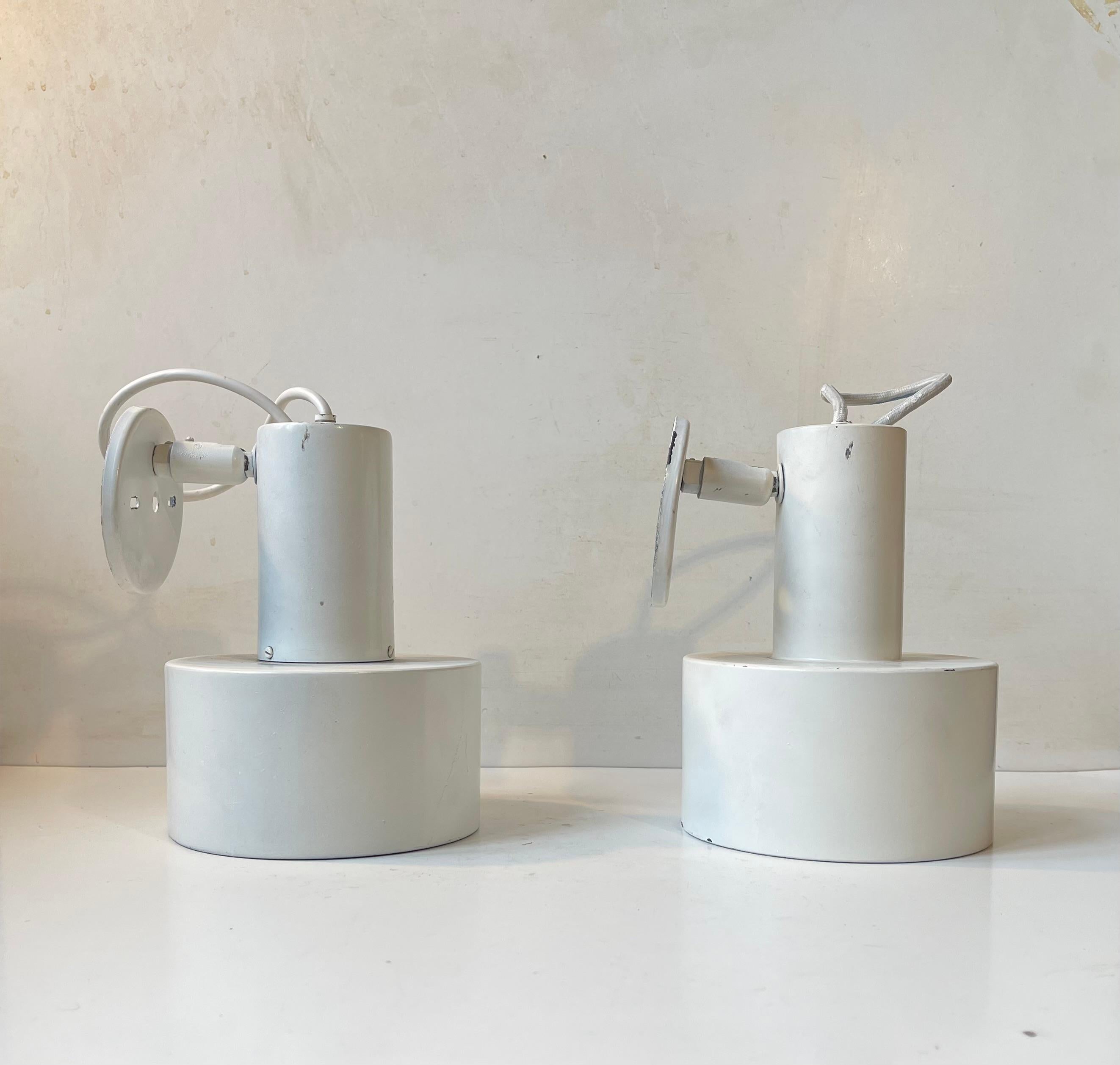 White adjustable wall lights by Louis Poulsen. Designed and manufactured during the 1970s in Denmark.The pair displays signs of use and patina especially to the bases. They feature original porcelain fittings up to 100 watts and internal light