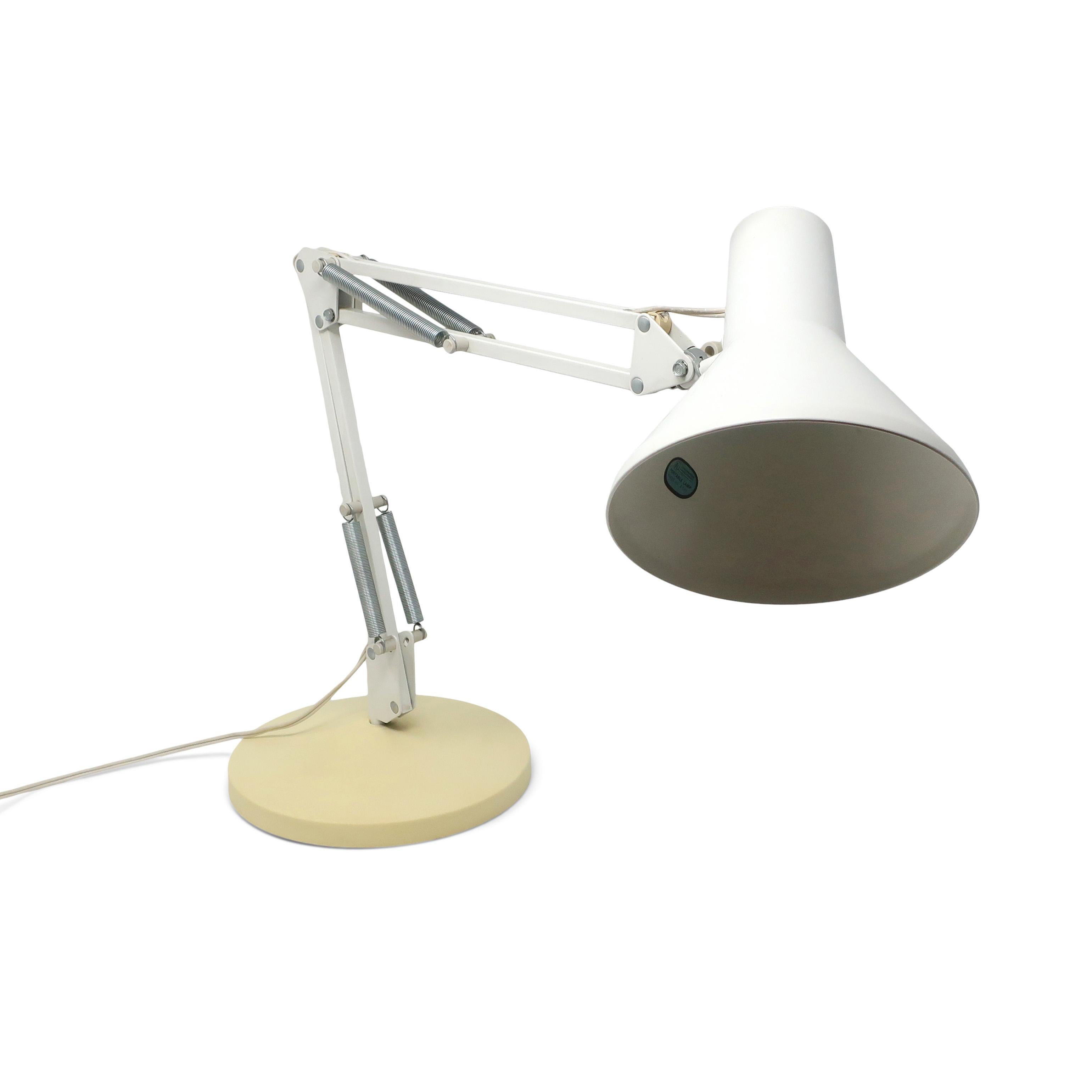 A vintage white Luxo desk lamp with a cream base. This design is similar to the Luxo L-1 lamp, which was the inspiration for the iconic Pixar animated short 