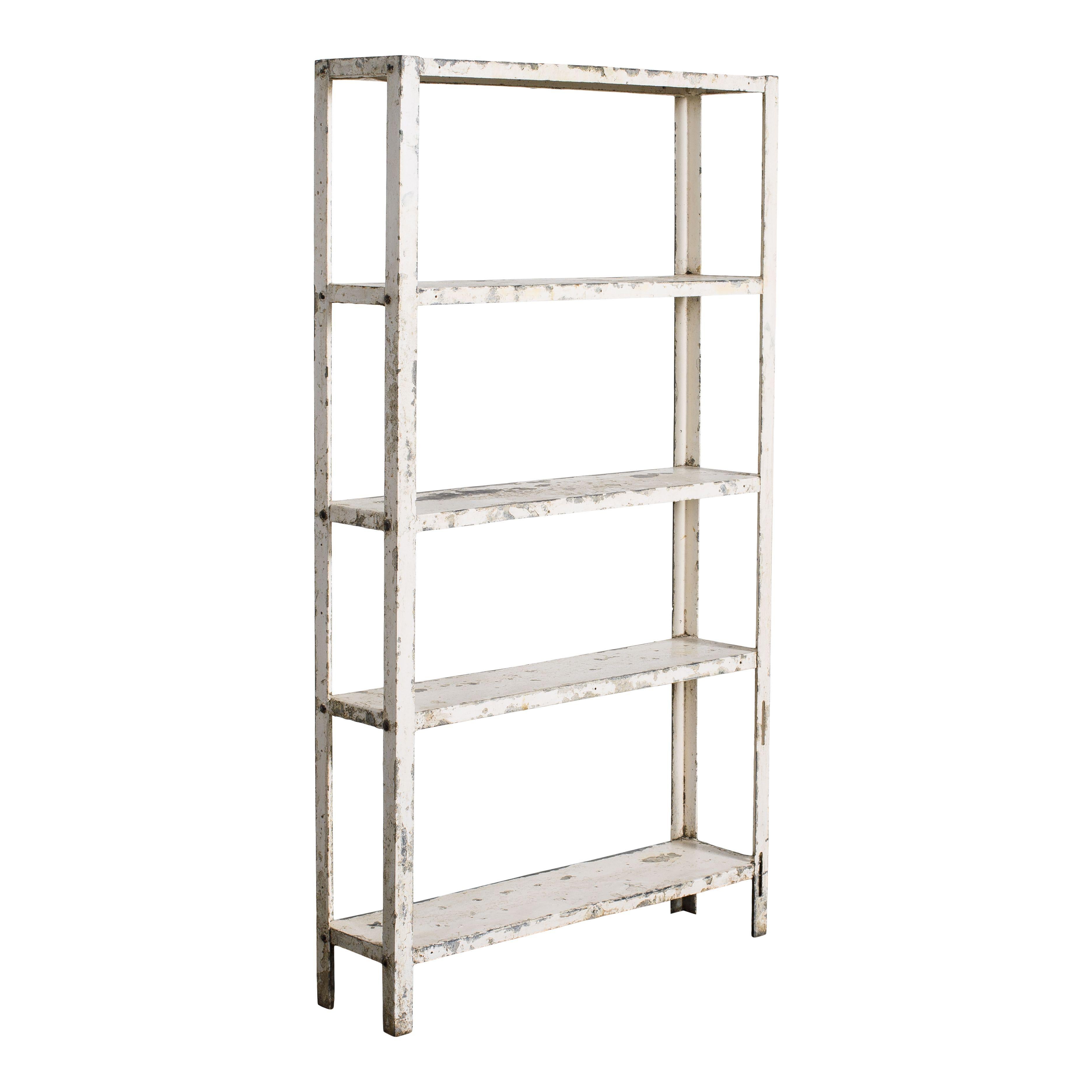 Un mobile vintage in metallo a scaffale aperto. Questo mobile ha 4 ripiani, 5 compreso quello superiore. Il semplice design in metallo lo rende un pezzo vintage classico e senza tempo. La vernice bianca scheggiata, inoltre, conferisce al pezzo