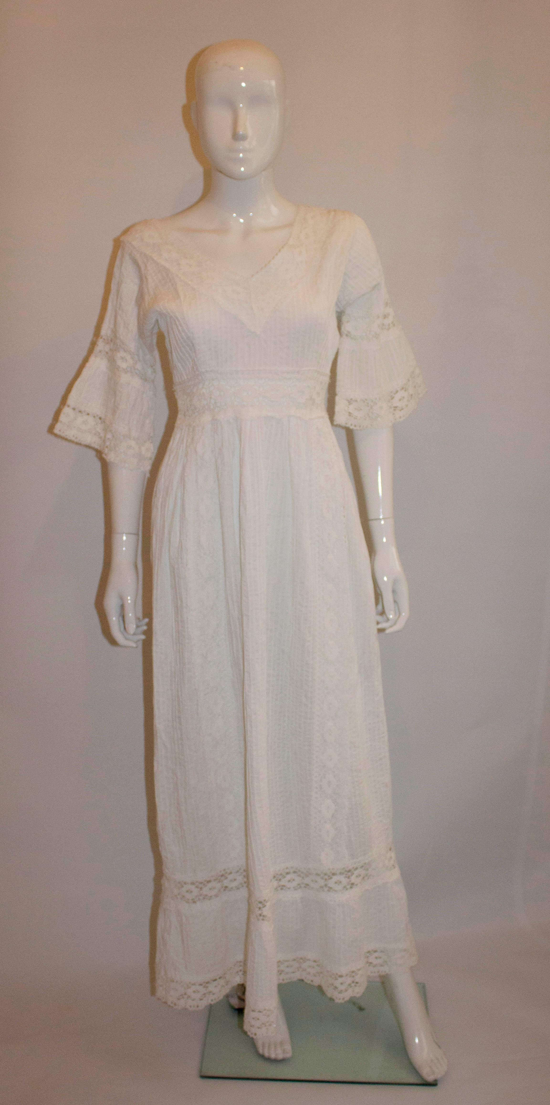 A wonderful vintage white evening gown. The dress has a v neckline and backline with a lot of pintuck detail. It has flared elbow length sleaves , a central back zip and lace detail at the hem.
Measurements: Bust 35'', waist 27'', length 60''