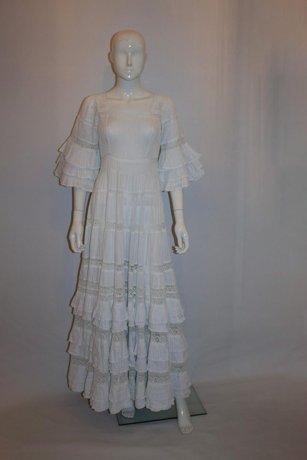 A headturning vintage gown by Mexicana.
This wonderful dress, would make a perfect wedding dress or frock for another special occassion. The dress has a square neckline front and back with a central back zip. It has elbow length sleaves with ruffles
