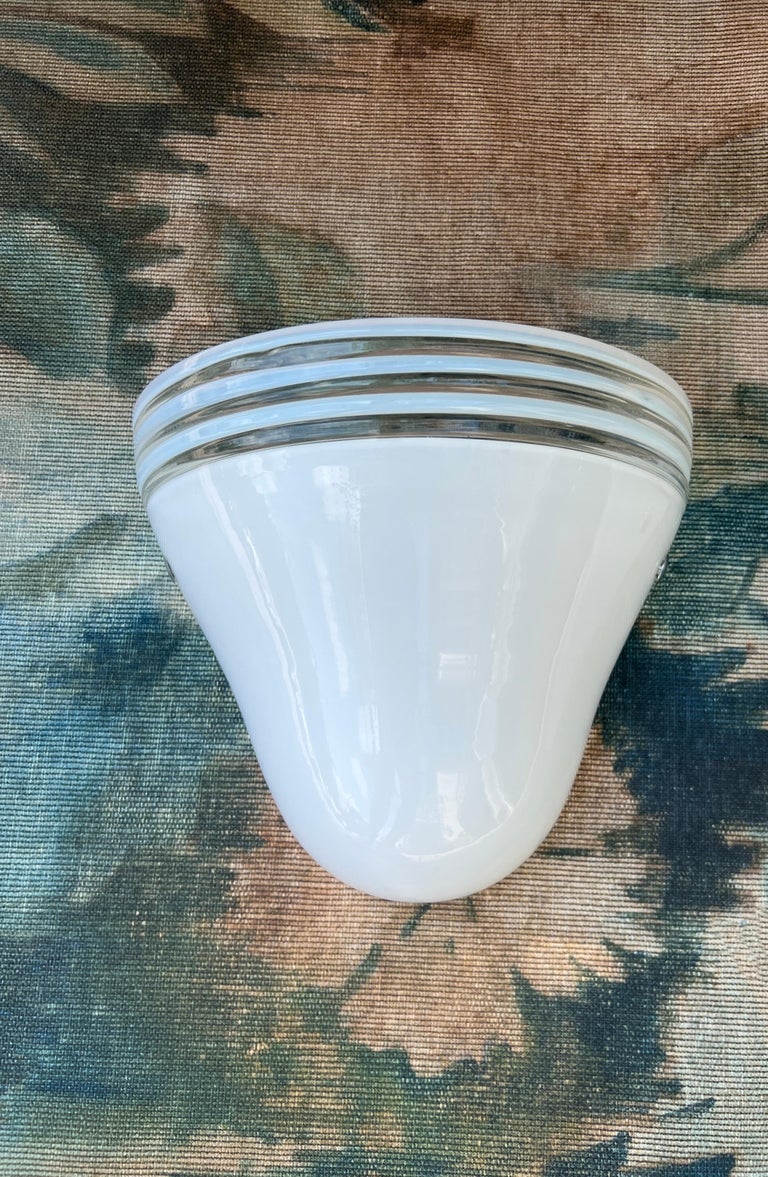 Mid-Century Modern sconce in white Murano glass designed by Roberto Pamio and Renato Toso for Leucos. The hand blown sconce has a diffuser shade in white glass and features clear glass stripes along the top. The sconce has two metal accents in