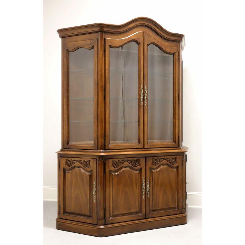 A French Country style china cabinet by White Furniture of Mebane, North Carolina, USA. Walnut with brass hardware. Upper cabinet has two glass doors, is lighted and has three angled adjustable glass shelves with plate grooves. Lower cabinet has