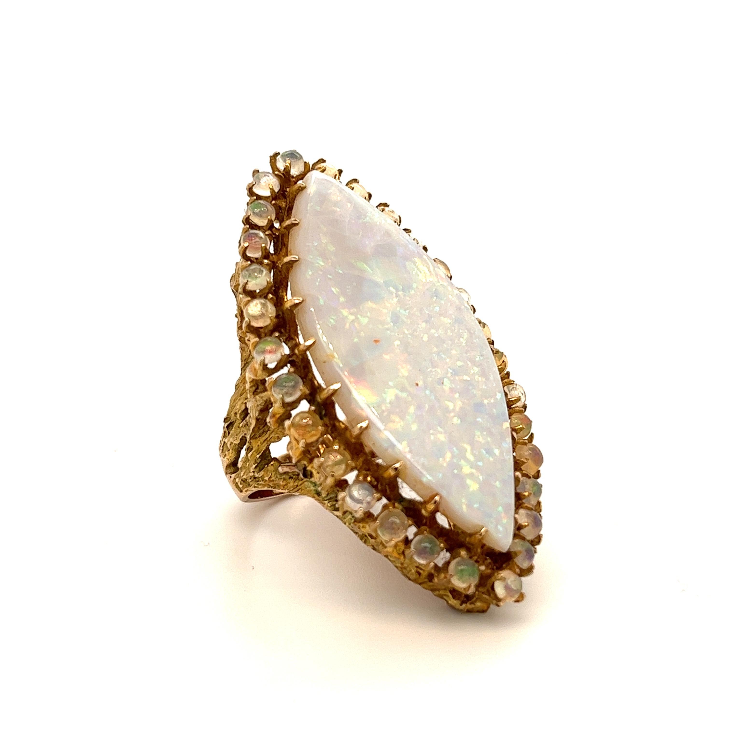 Natural marquise-shaped White Opal set in a halo of 30 ball-shaped natural Opal gemstones. The Opals are set in 14k solid yellow gold. The ring mounting is handmade in a tree-like design that blossoms upwards into the halo set Opals. A piece certain