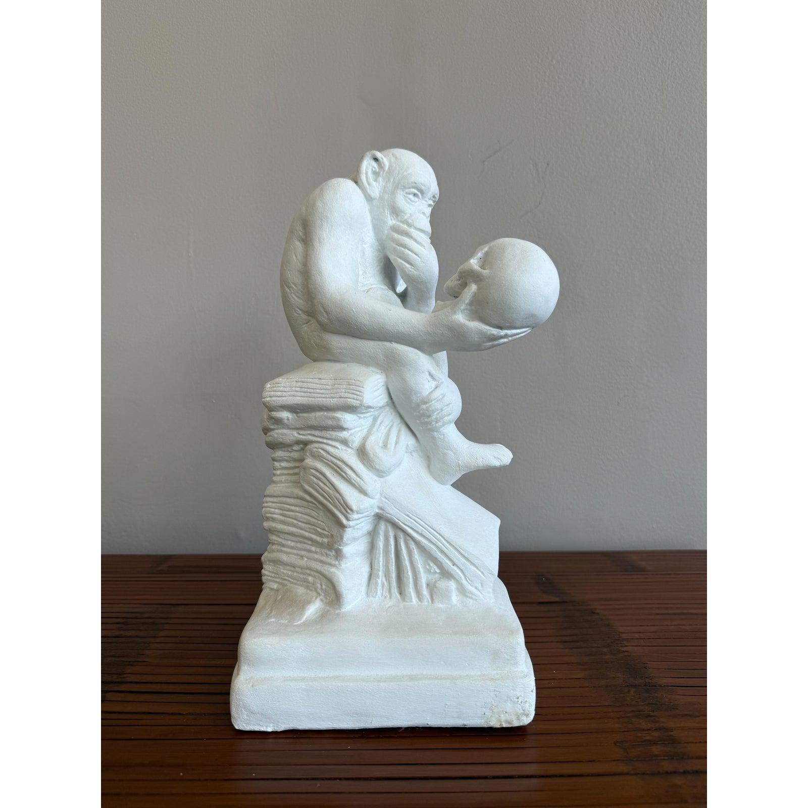 Scultura d'epoca unica e contemplativa di una scimmia in posa pensierosa che tiene in mano un teschio umano seduto su un libro aperto. Un'interpretazione surreale de 