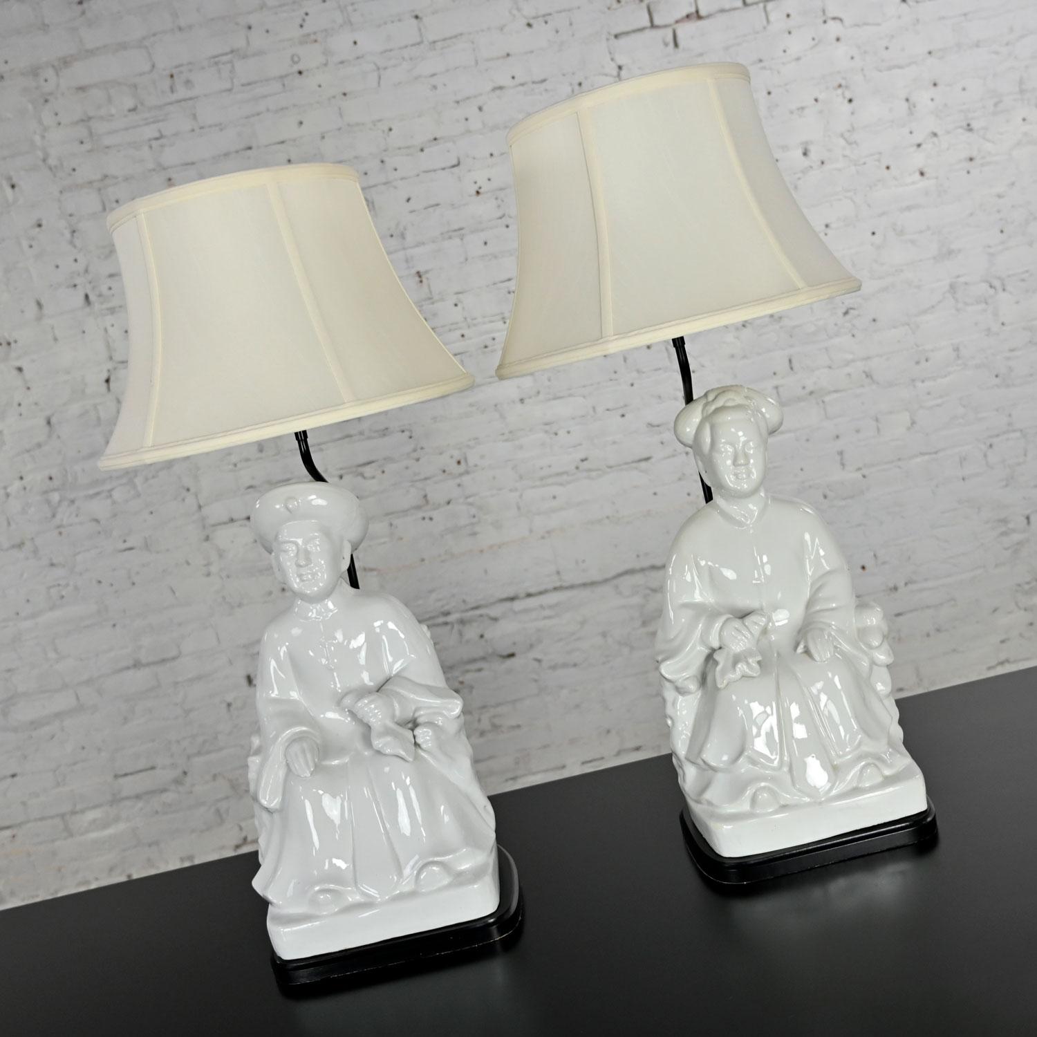 Fabulous vintage white porcelain Blanc De Chine large scale Asian figure chinoiserie pair of lamps with off-white silk-like bell shades and black bases. Beautiful condition, keeping in mind that these are vintage and not new so will have signs of