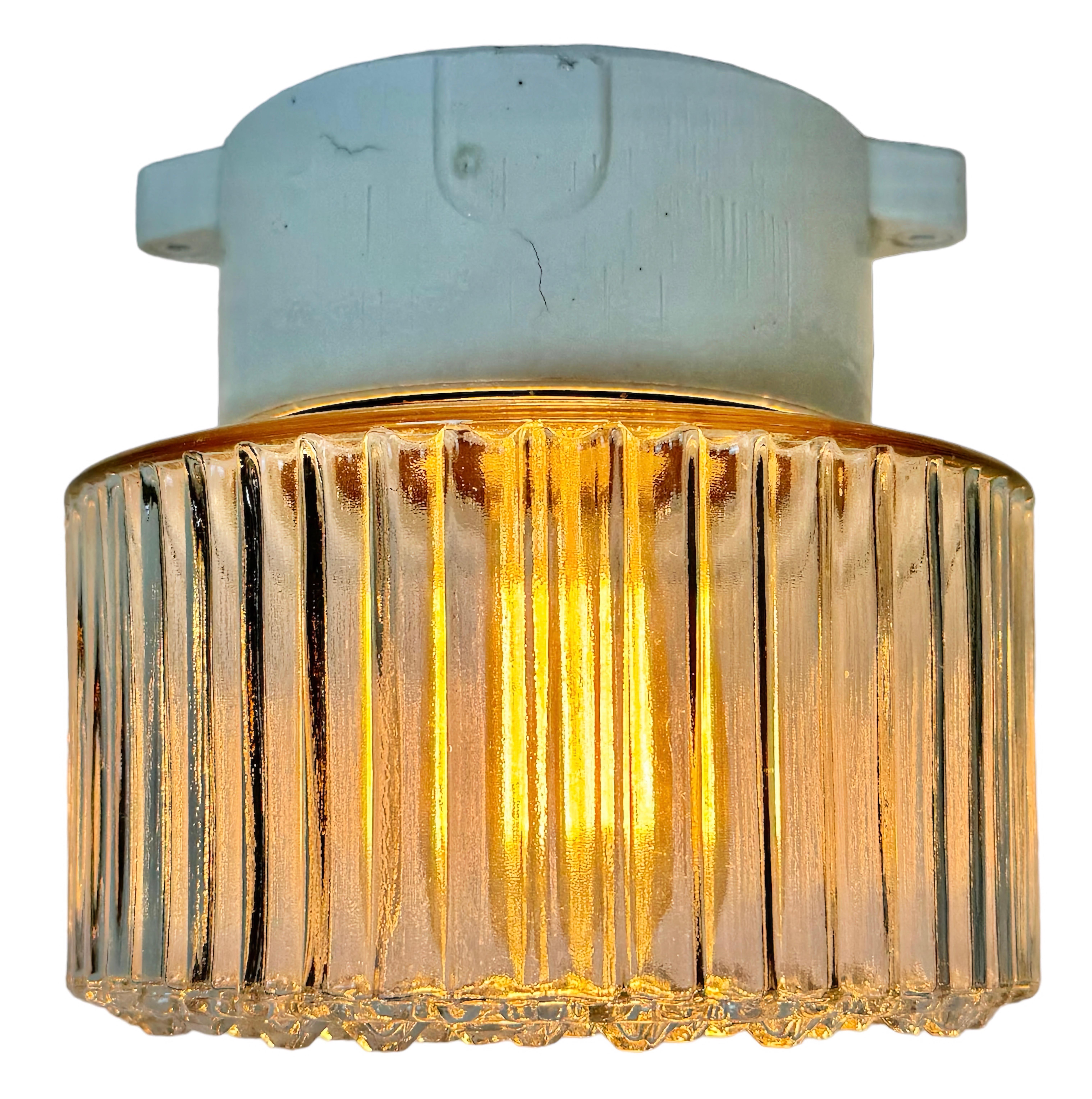 Vintage ceiling or wall light  made in East Germany during the 1970s. It features a white porcelain wall mounting and a glass cover. The socket requires E27/E 26 light bulbs. New wire. The weight of the lamp is 2,4 kg.
Dimensions: 
Diameter of the