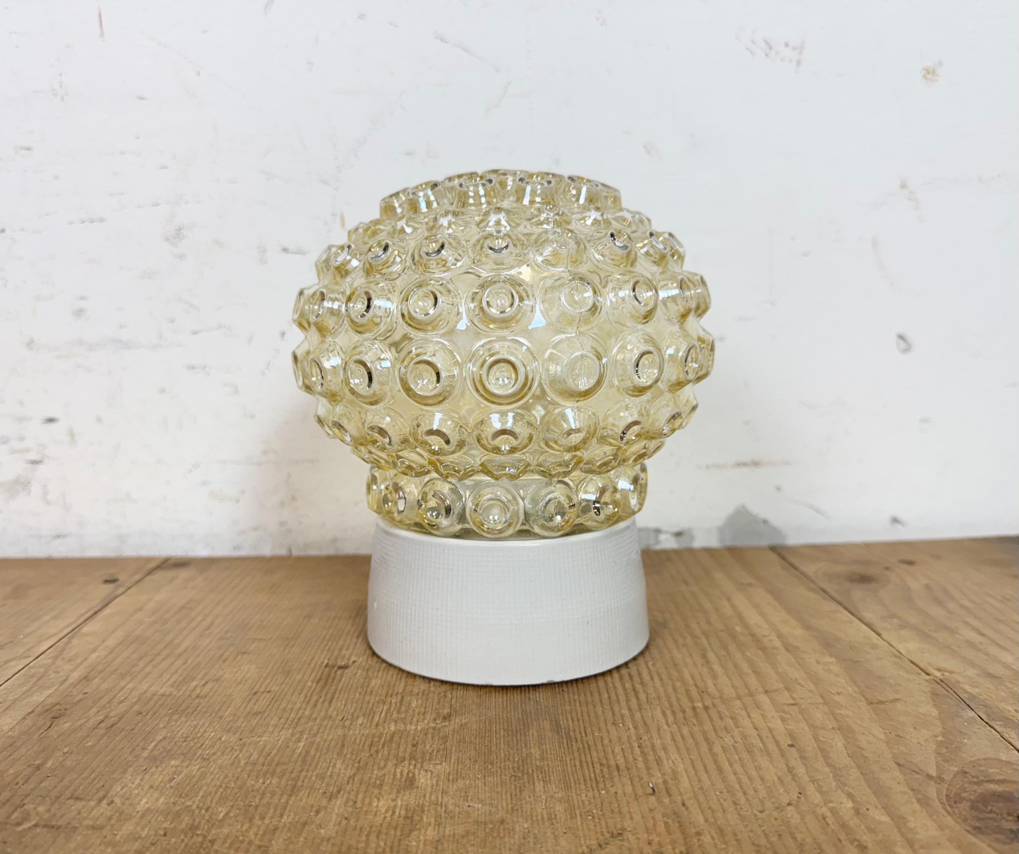 Vintage industrial ceiling or wall light  made in former Czechoslovakia during the 1970s. It features a white porcelain wall or ceiling mounting and a glass cover. The socket requires E27/E 26 light bulbs. New wire. The weight of the lamp is 1