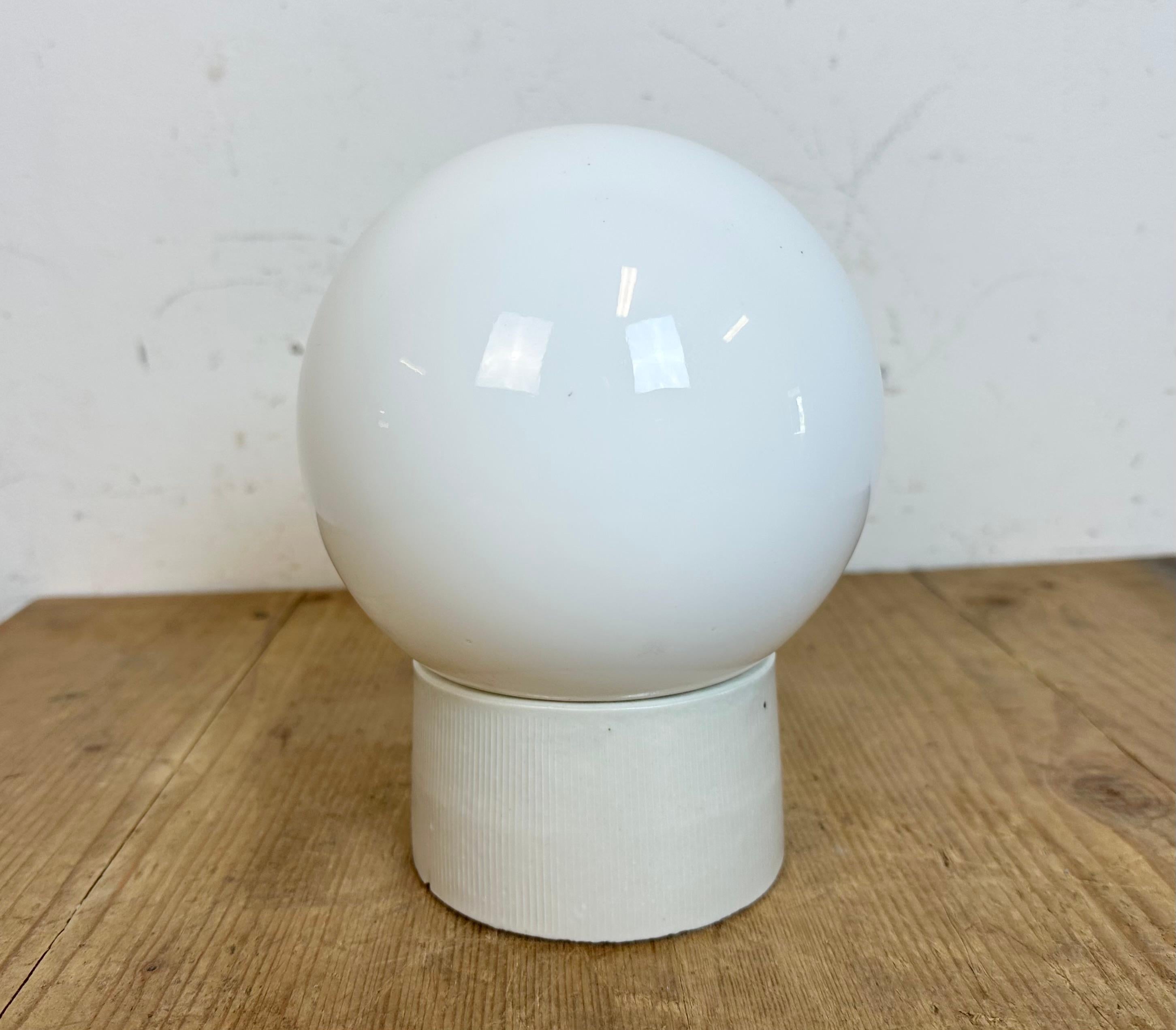 Vintage industrial ceiling or wall light  made in former Czechoslovakia during the 1960s. It features a white porcelain wall mounting and a milk glass cover. The socket requires E27/E 26 light bulbs. New wire. The weight of the lamp is 1