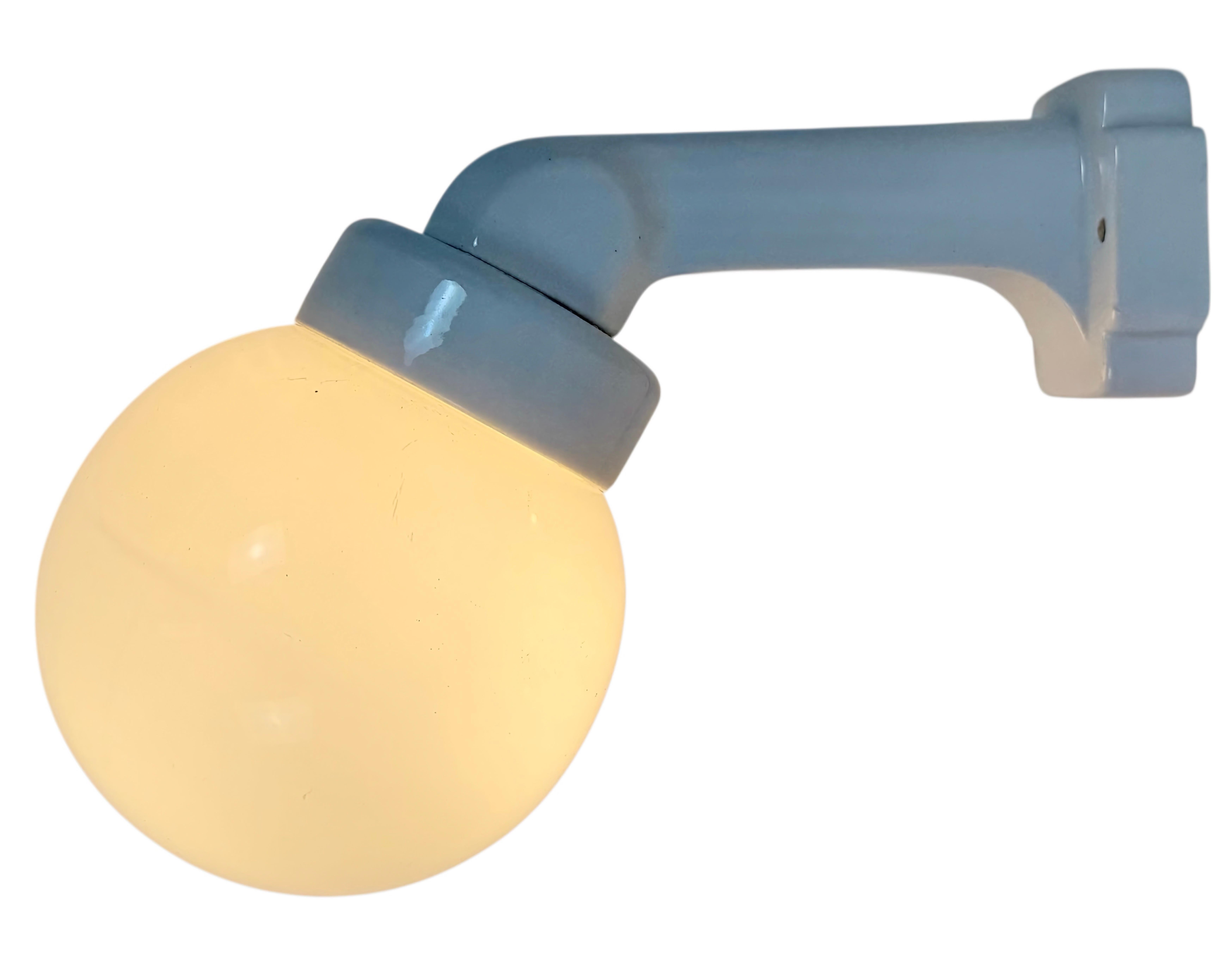 Applique industriale vintage realizzata nell'ex Cecoslovacchia negli anni '50. Presenta un supporto a parete in porcellana bianca e un coperchio in vetro trasparente. La presa richiede lampadine standard E 27/ E 26. Un nuovo cavo. Il peso della