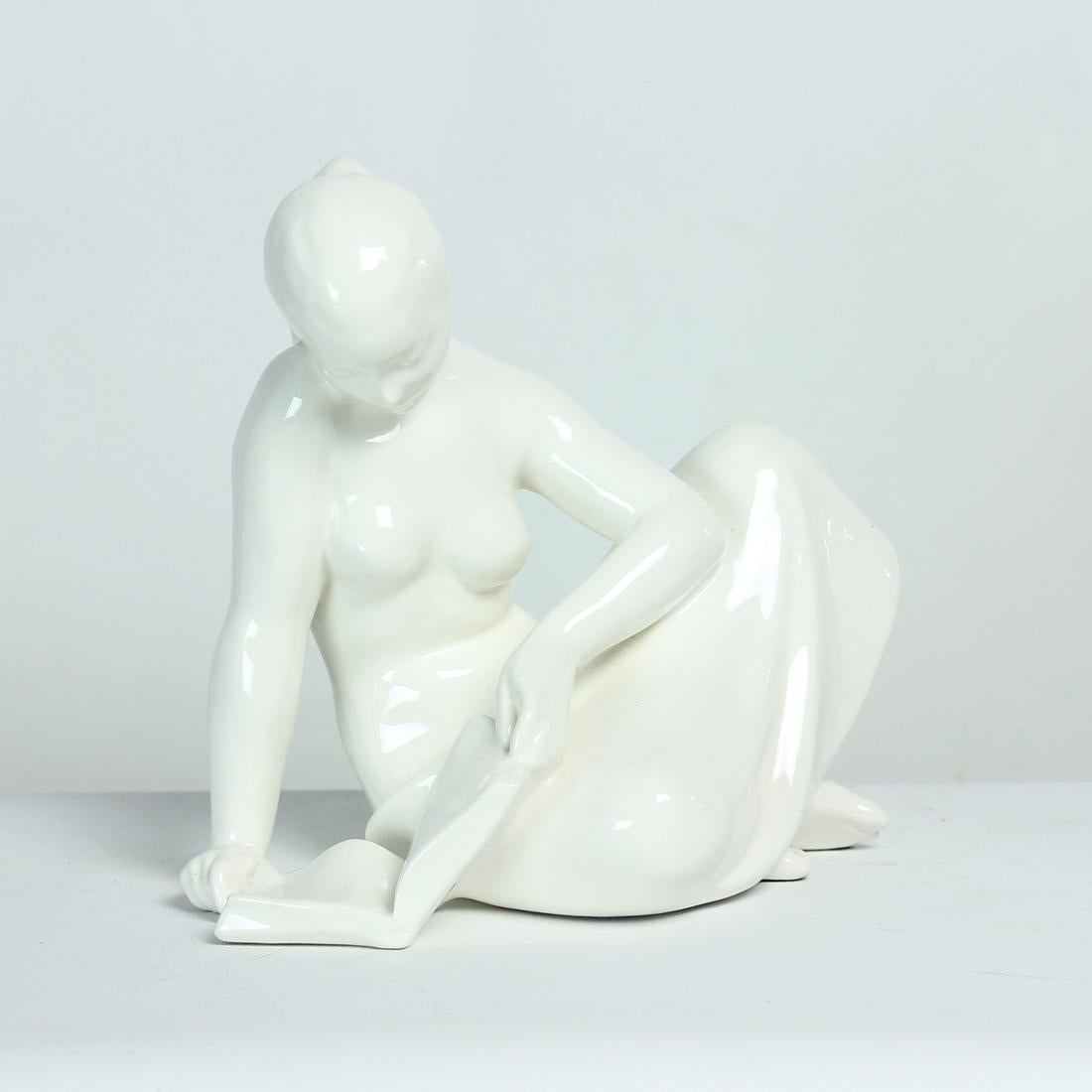 Belle statue vintage en porcelaine produite par la société Jihokera dans les années 1960. Tampon d'origine partiellement visible sur le fond. La statue est en porcelaine blanche émaillée. Elle montre une femme lisant un livre. La statue a l'air