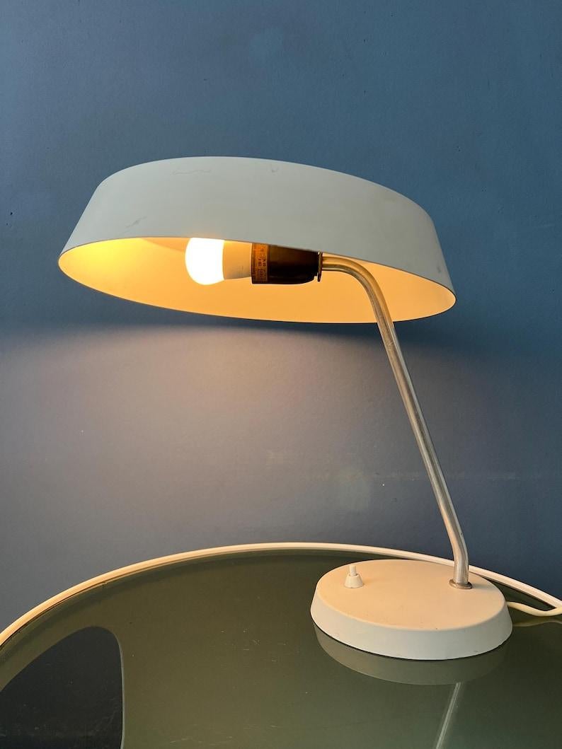 Beautiful white/beige VEB Leuchten desk lamp in bauhaus style design. The piece is made out of metal. The lamp requires one E27/26 (standard) lightbulb and currently has an EU plug (easily usable outside EU with plug-converter).

Additional