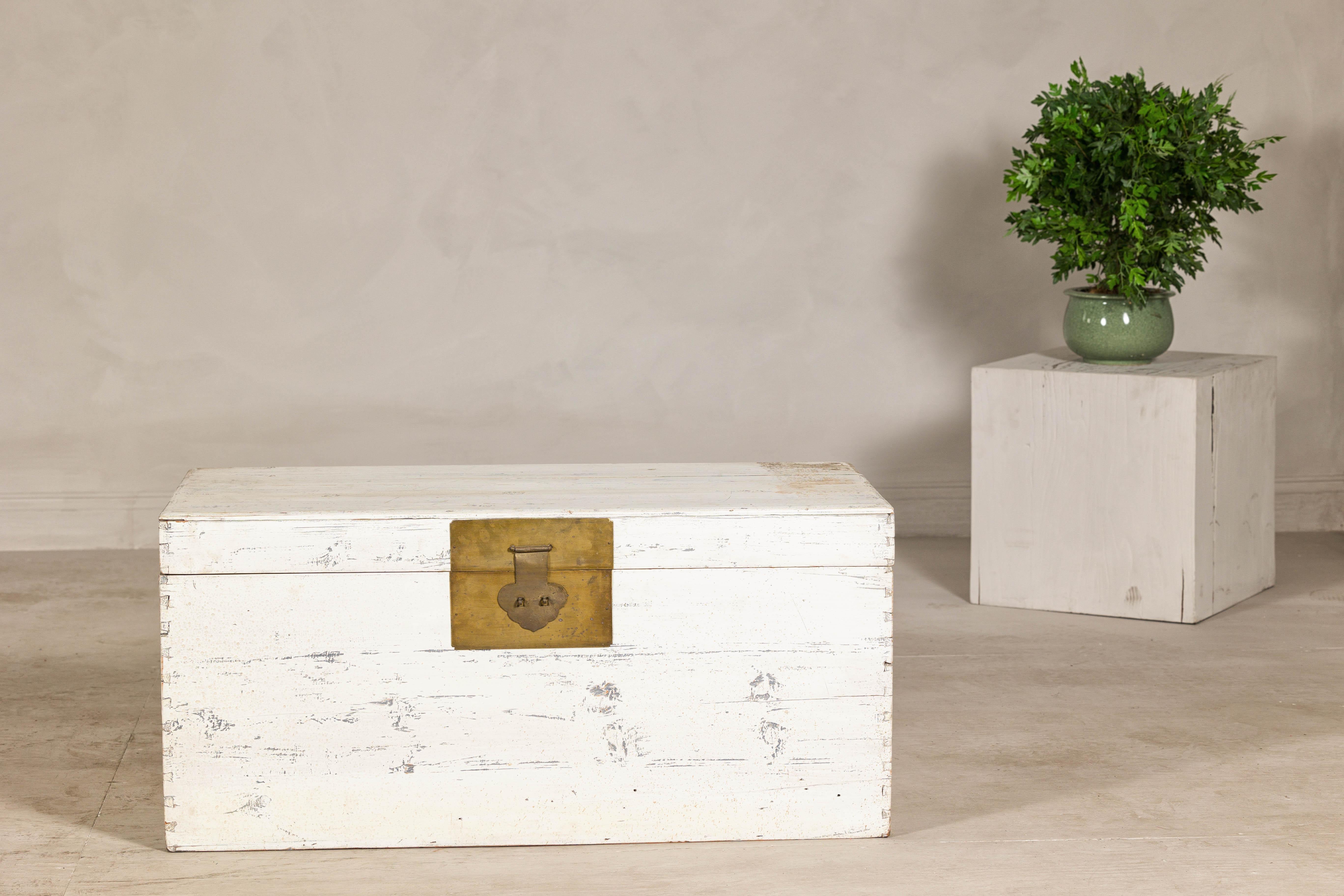 Un coffre à couvertures vintage avec une finition blanche joliment altérée, cette pièce polyvalente exsude un charme rustique et une élégance discrète. Fabriquée en bois léger, probablement du pin, la commode présente un assemblage à queue d'aronde