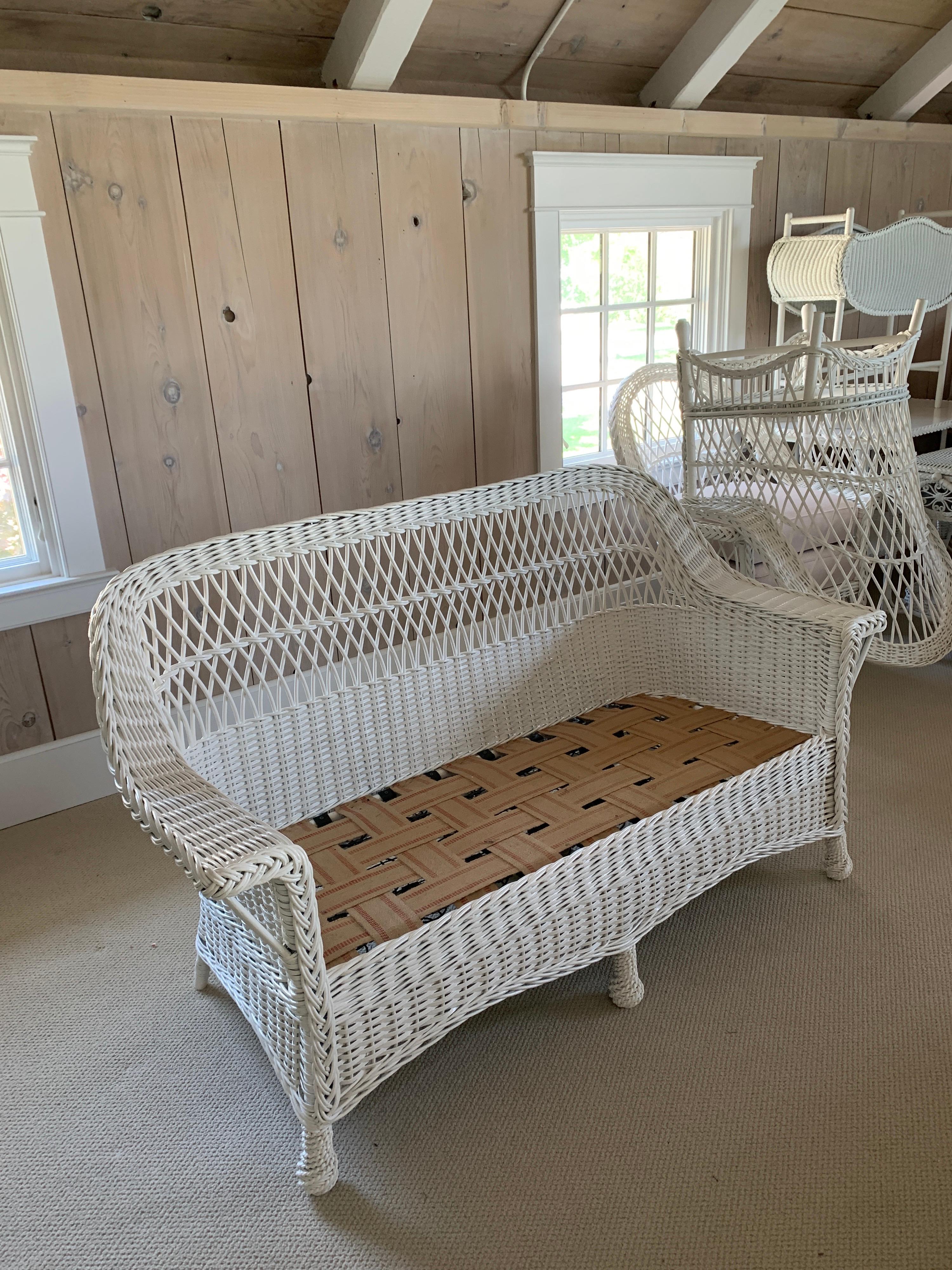 A small scale white wicker sofa measuring 60” wide, 28” deep, 34” tall with a seat platform at 13”.