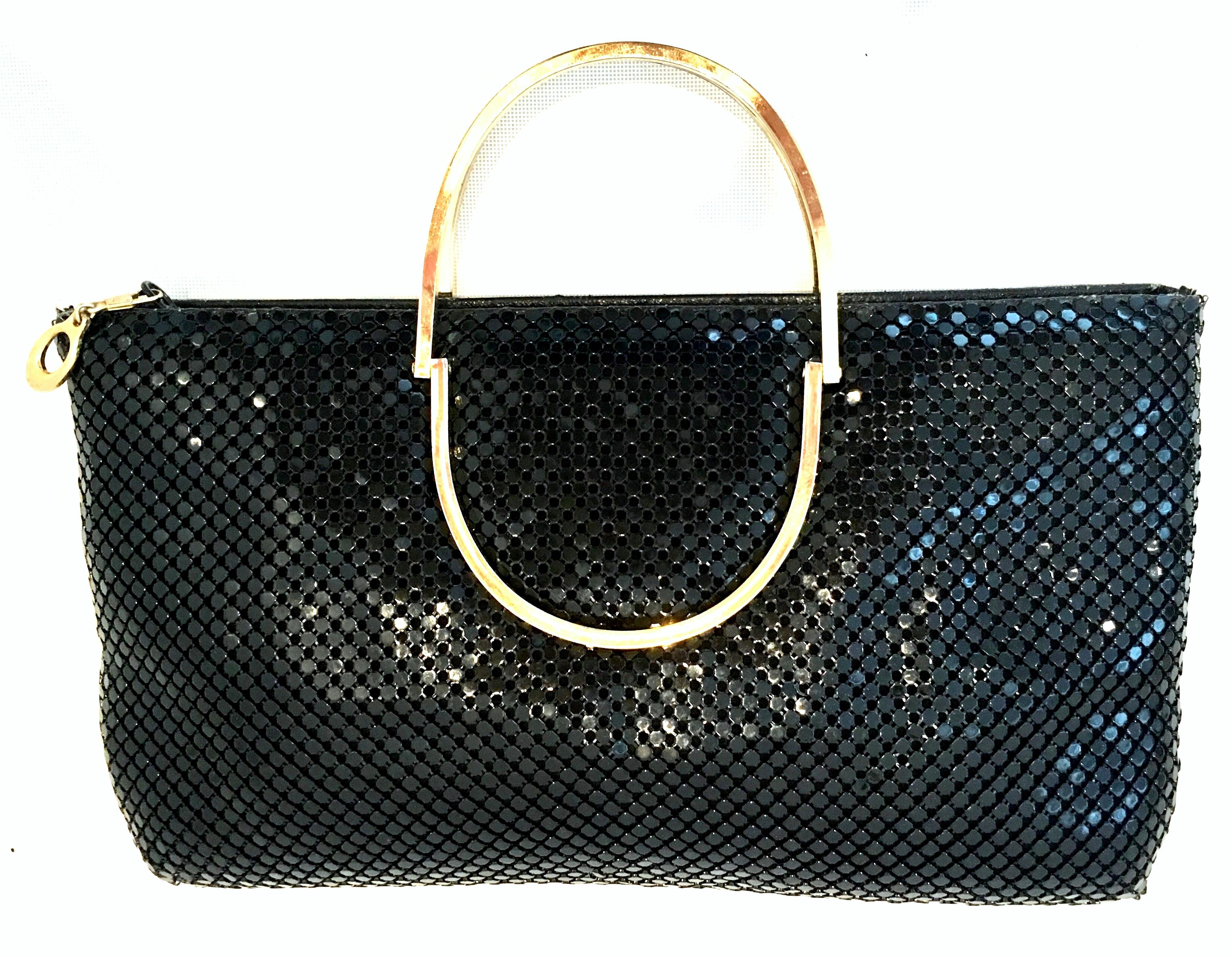 20th Century Black Metal Mesh and Gilt Brass Handle Hand Bag By, Whiting & Davis. This unique hand bag features Whiting & Davis iconic metal mesh in jet black with a double circular gilt brass carrying handle. There is a zip closure with a gold