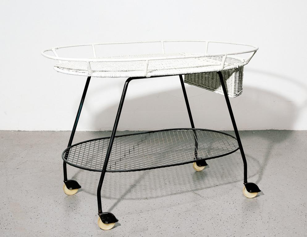 Vintage bar cart by Salterini. White painted wicker top and basket over black steel frame. On casters.