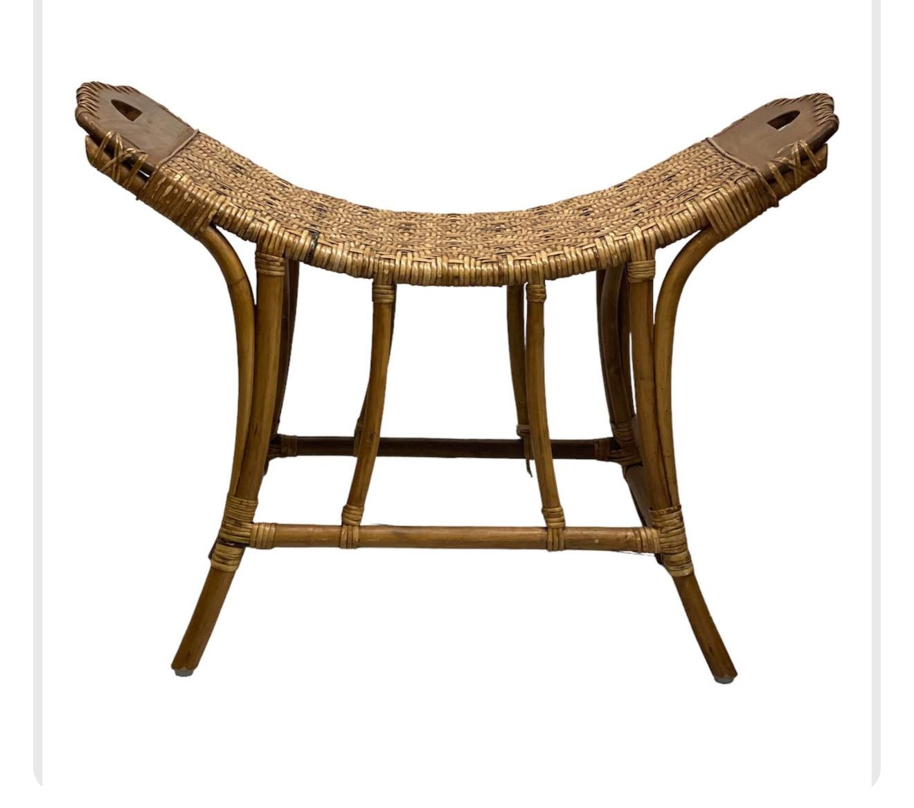 This vintage bench features a curved, woven wicker seat with a tight, herringbone pattern, supported by a bamboo frame. The legs are slightly angled for stability, with cross-bracing for added support, all wrapped with wicker at the joints. The ends