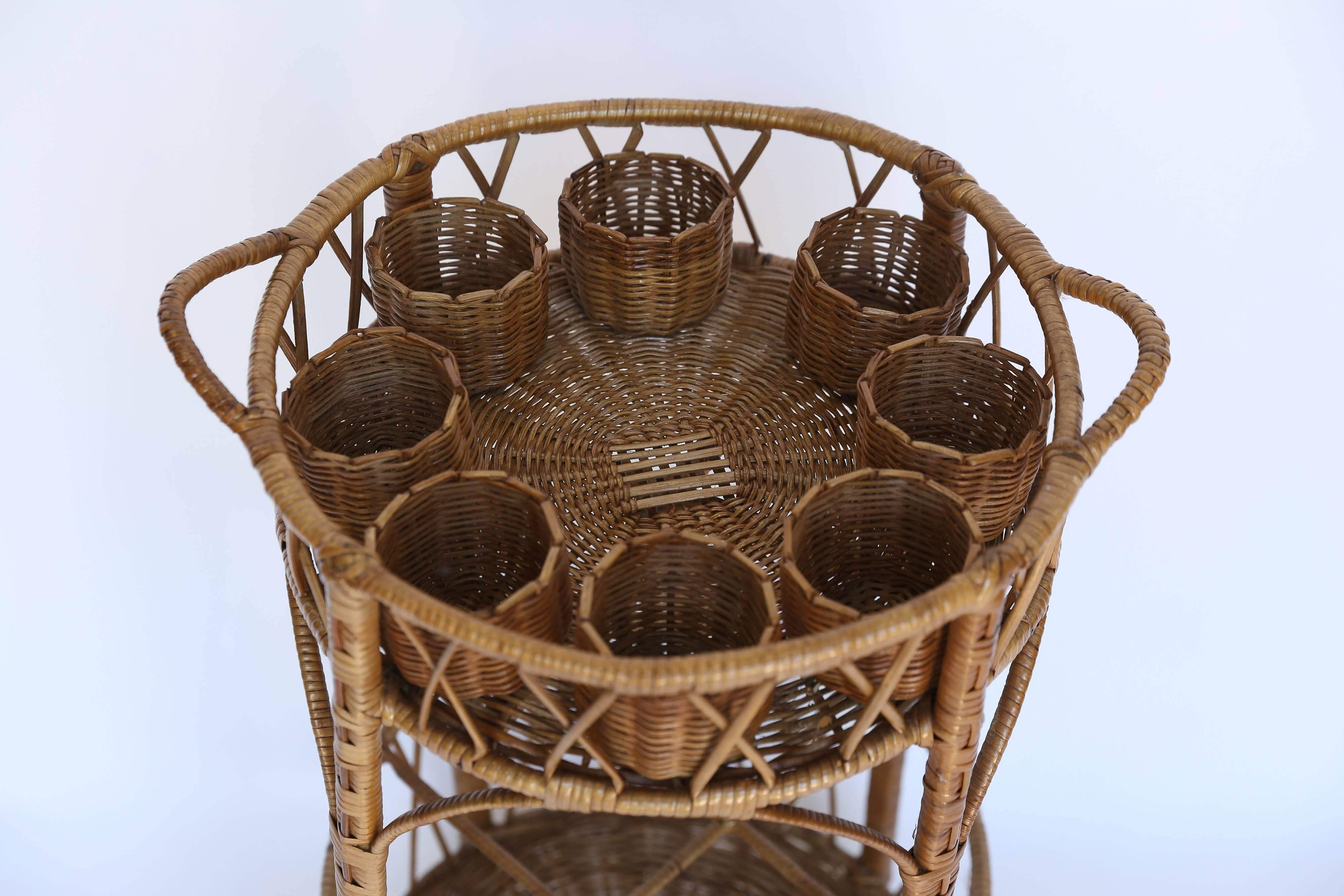 An eye-catching and fun vintage bar table in wicker. With eight glass holders on the top level and the bottom divided into 4 sections for bottles and accessories, it is in near perfect condition.