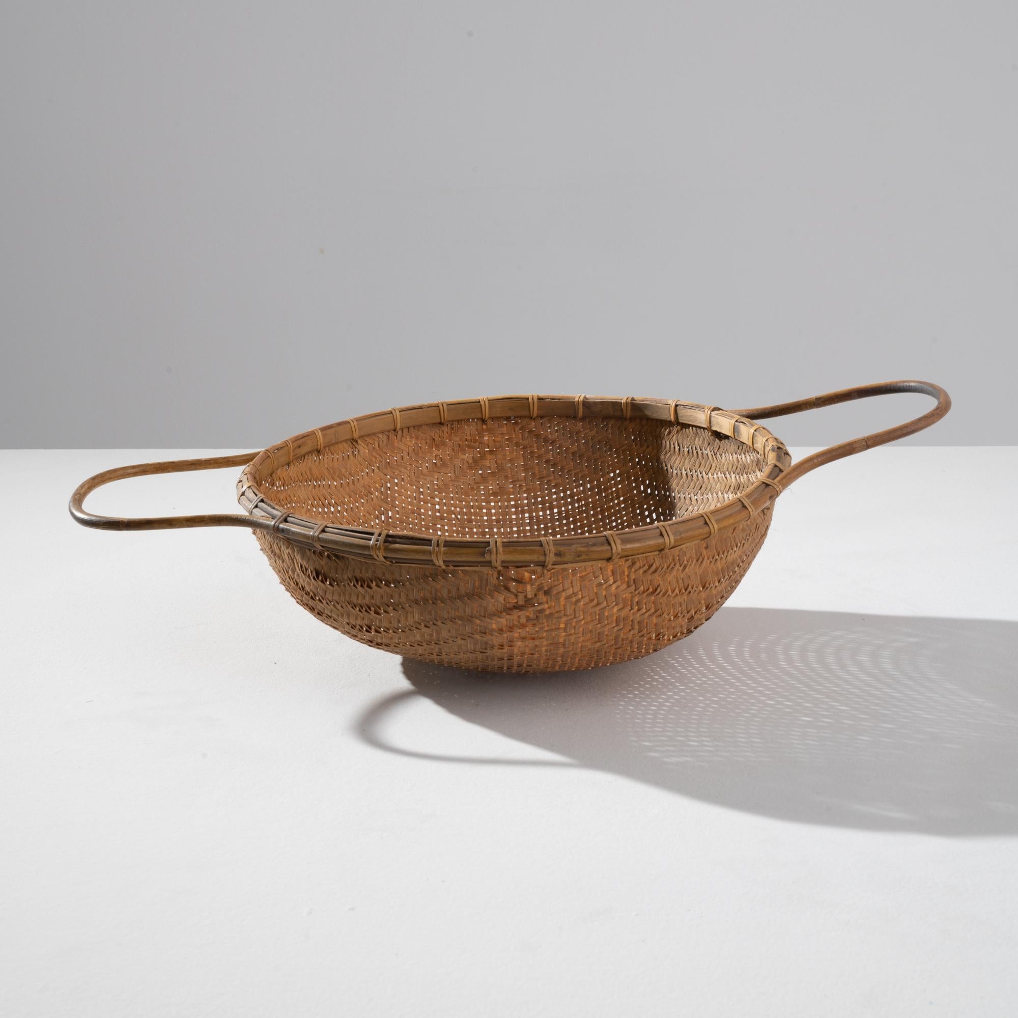 This beautiful vintage wicker basket has a timeless simplicity. Rustic and handcrafted, a bowl of woven rushes is finished with a circular band of bent cane; the sinuous line of the handles displays a mastery of these ancient Craft techniques. The