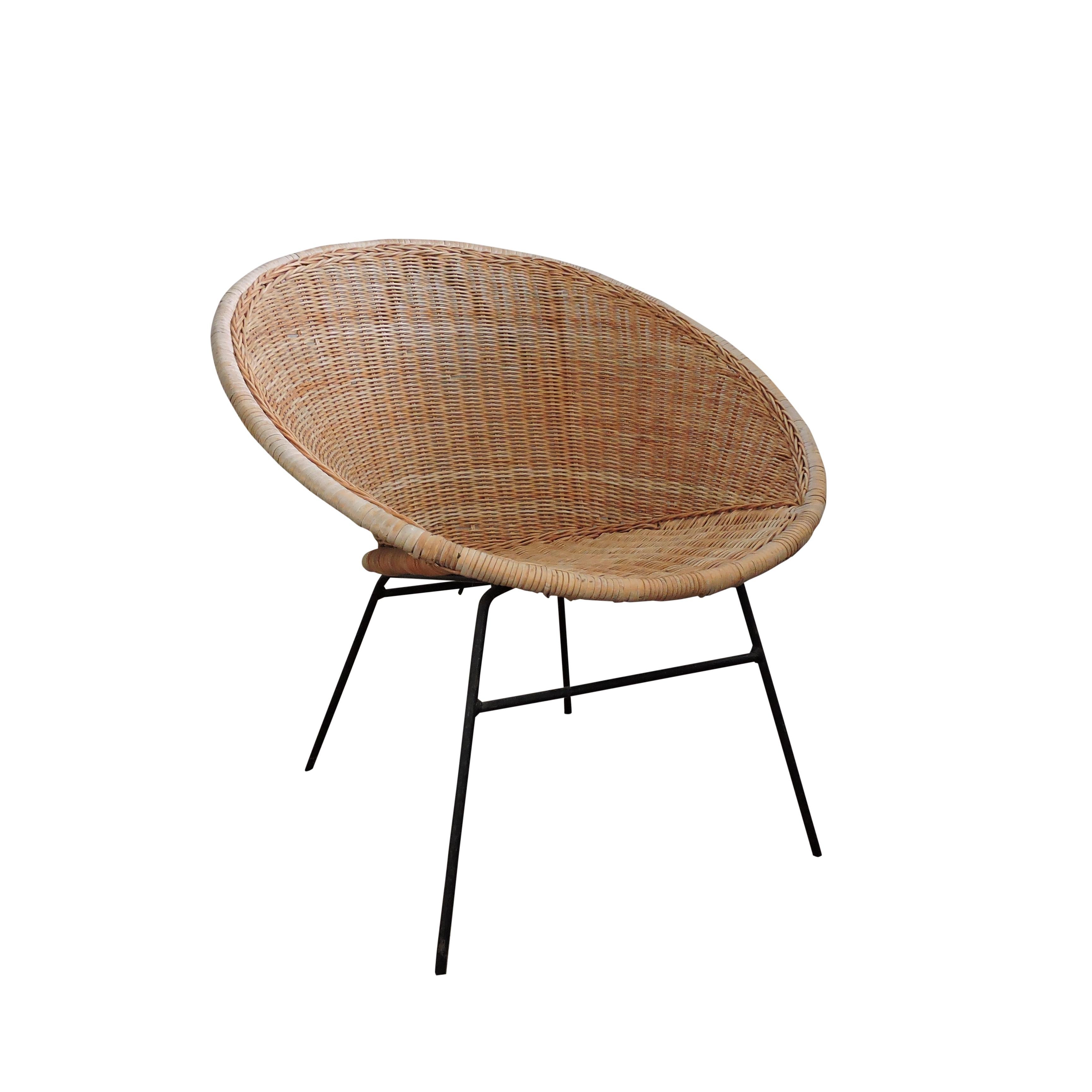 A 1970s wicker bucket chair standing on four metal legs.