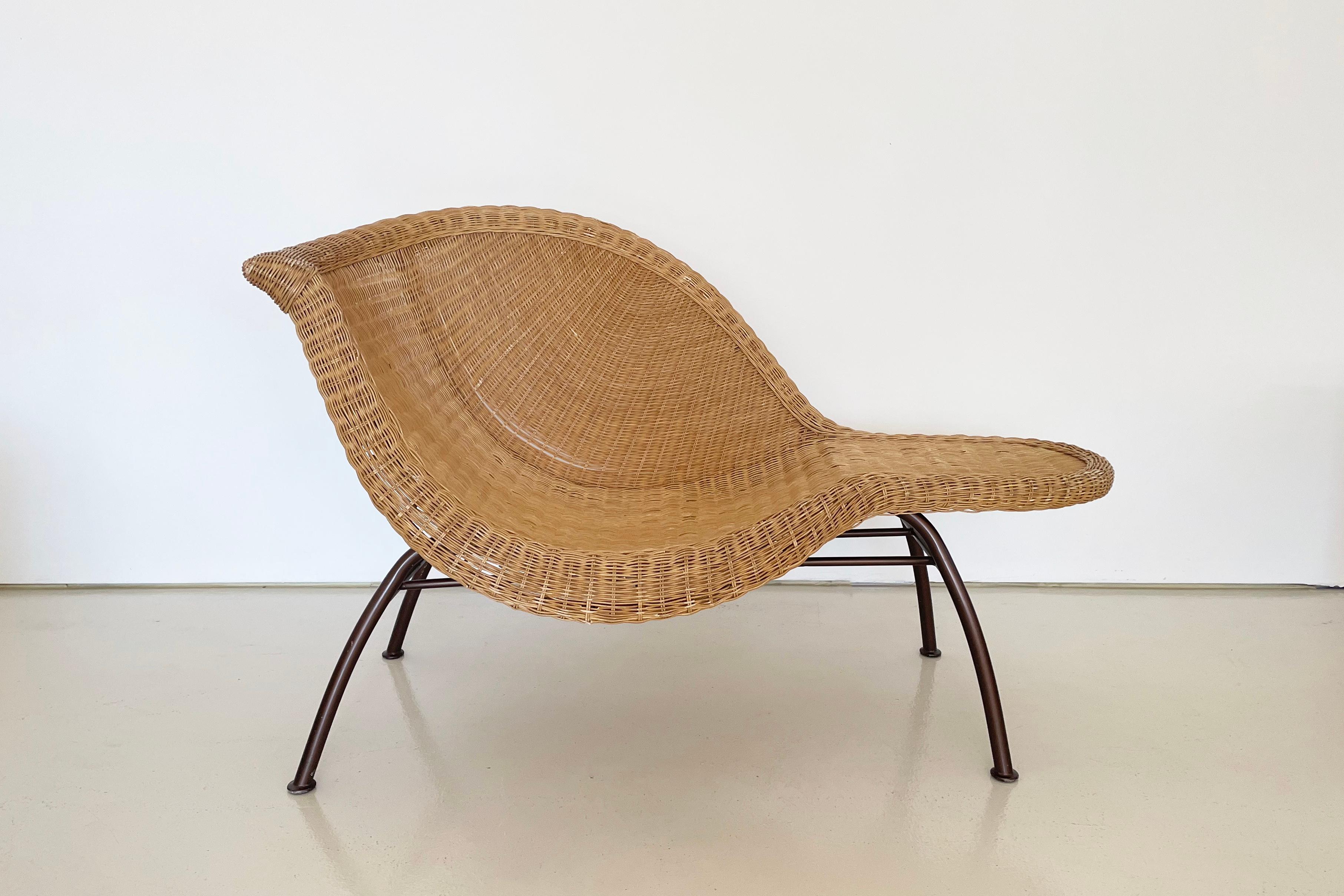 Believed to be 1970s.

The asymmetrical, natural woven, wicker seat allows for a lounging position or use as a seat with a table-like surface to on side. 

There is some broken wicker in various places. All wear has been thoroughly documented in the