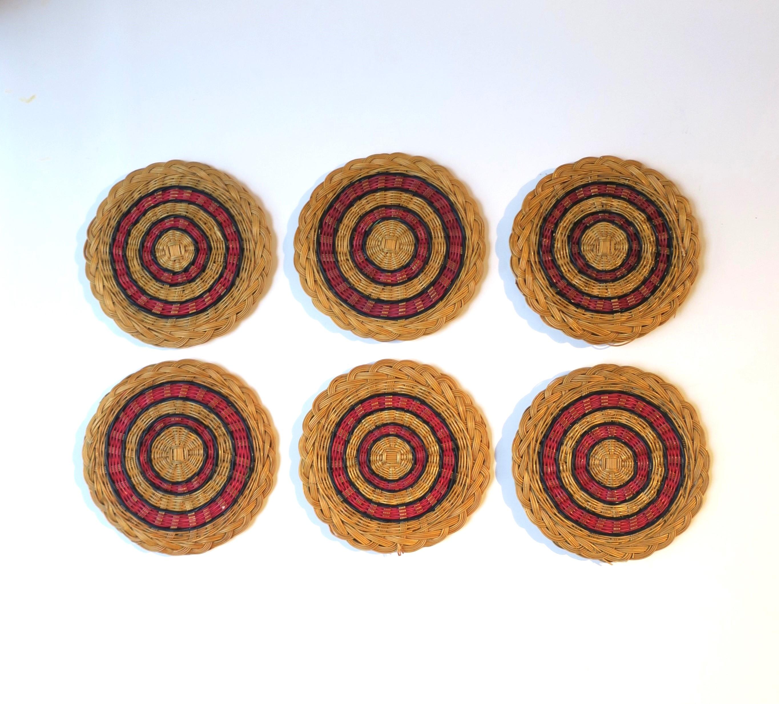 A vintage set of six (6) wicker drinks cocktails coasters, in the American Classical style, circa mid-20th century, 1960s. Coasters are a natural tan hue, with braided edge, and a red and blue circular design. A great addition to any bar, bar cart,
