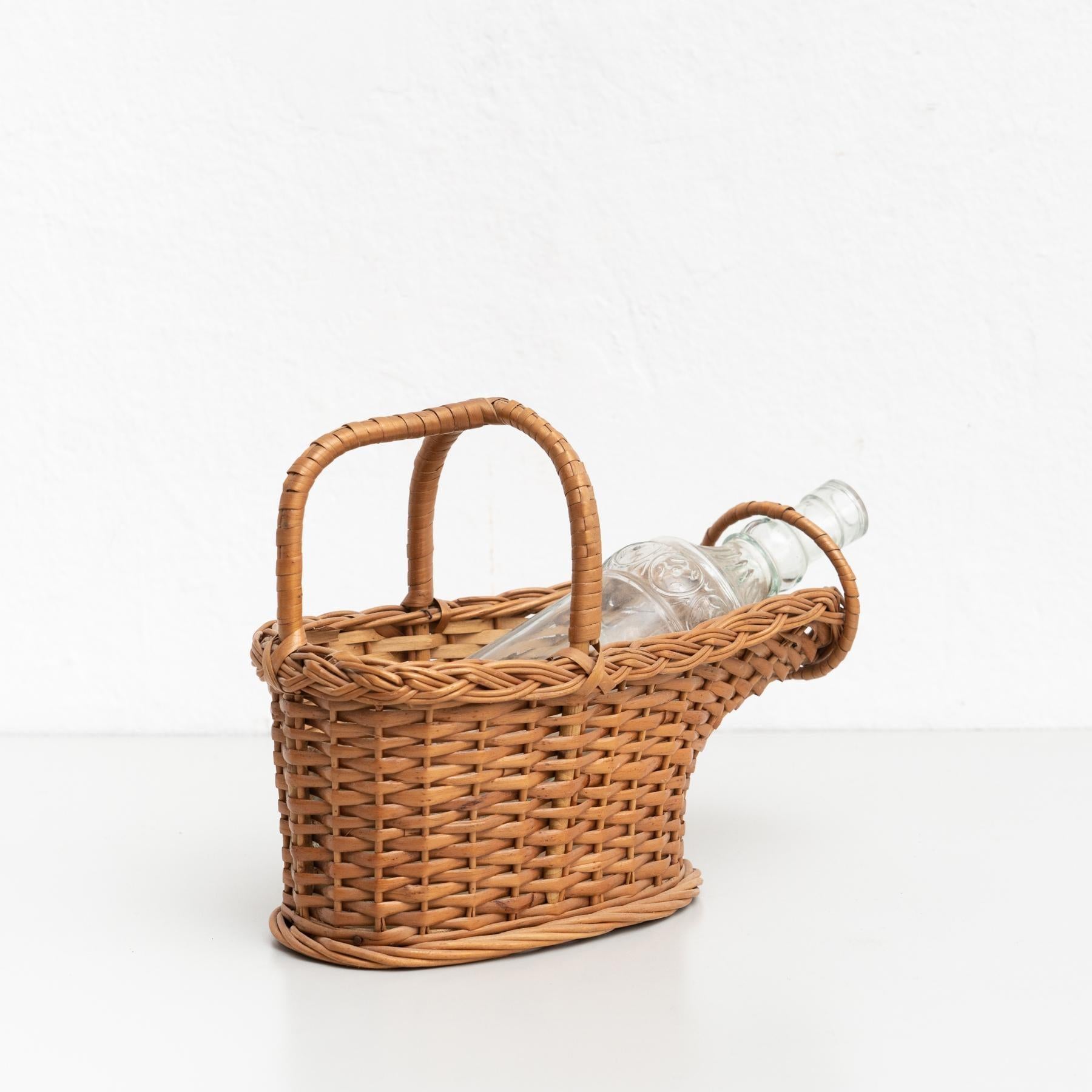 Portabottiglie vintage in vimini.    Prodotto in Spagna da un produttore sconosciuto, circa 1970    In condizioni originali, con lievi usure dovute all'età e all'uso, conserva una bella patina.    Materiali:  Vimini  Vetro.