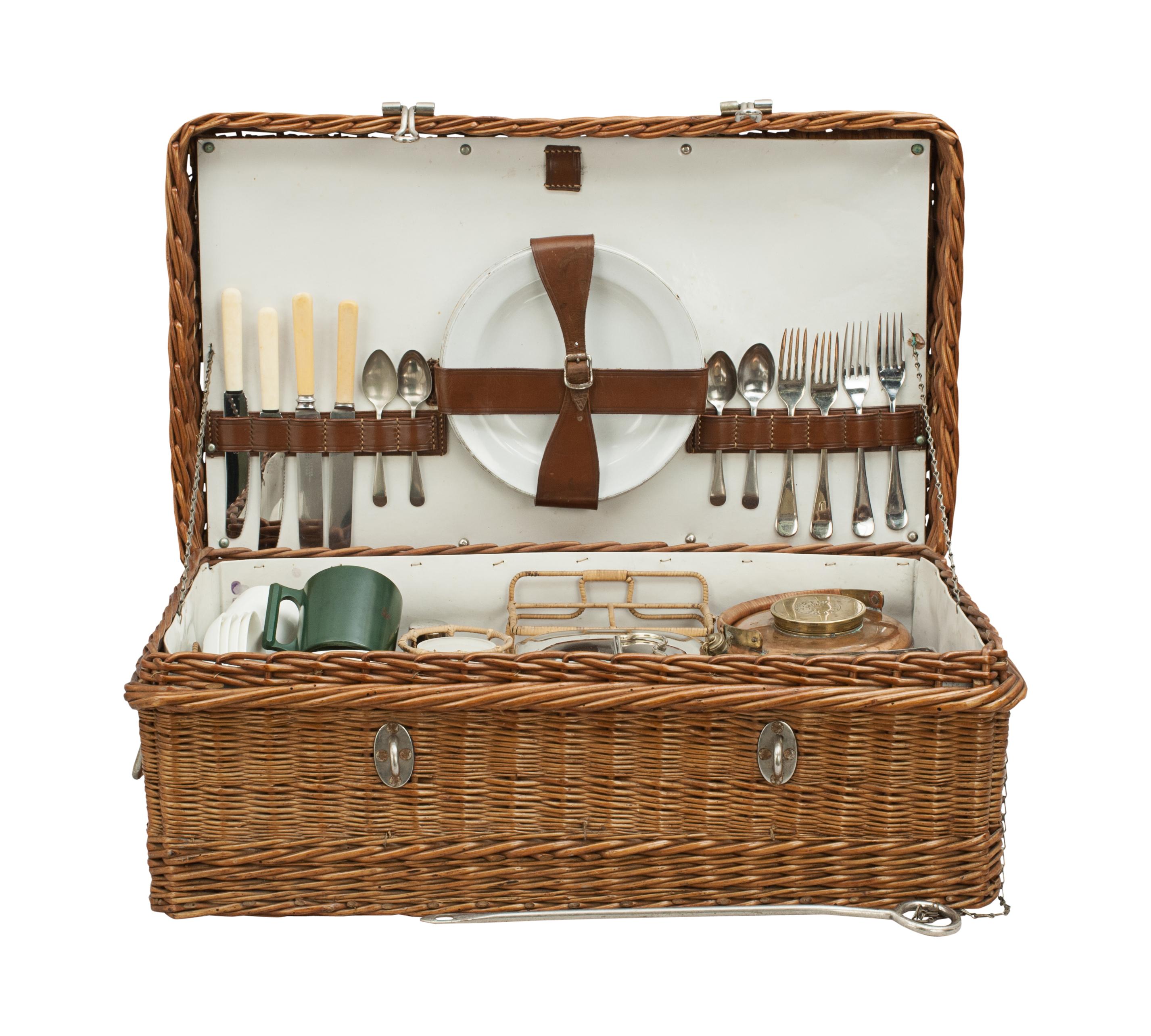 Vintage picnic set.
A charming wicker basket four person picnic set with metal carry handles on both sides and a lockable metal bar at the front. The contents are held in place in the lid by leather strapping and in the base by an internal wicker