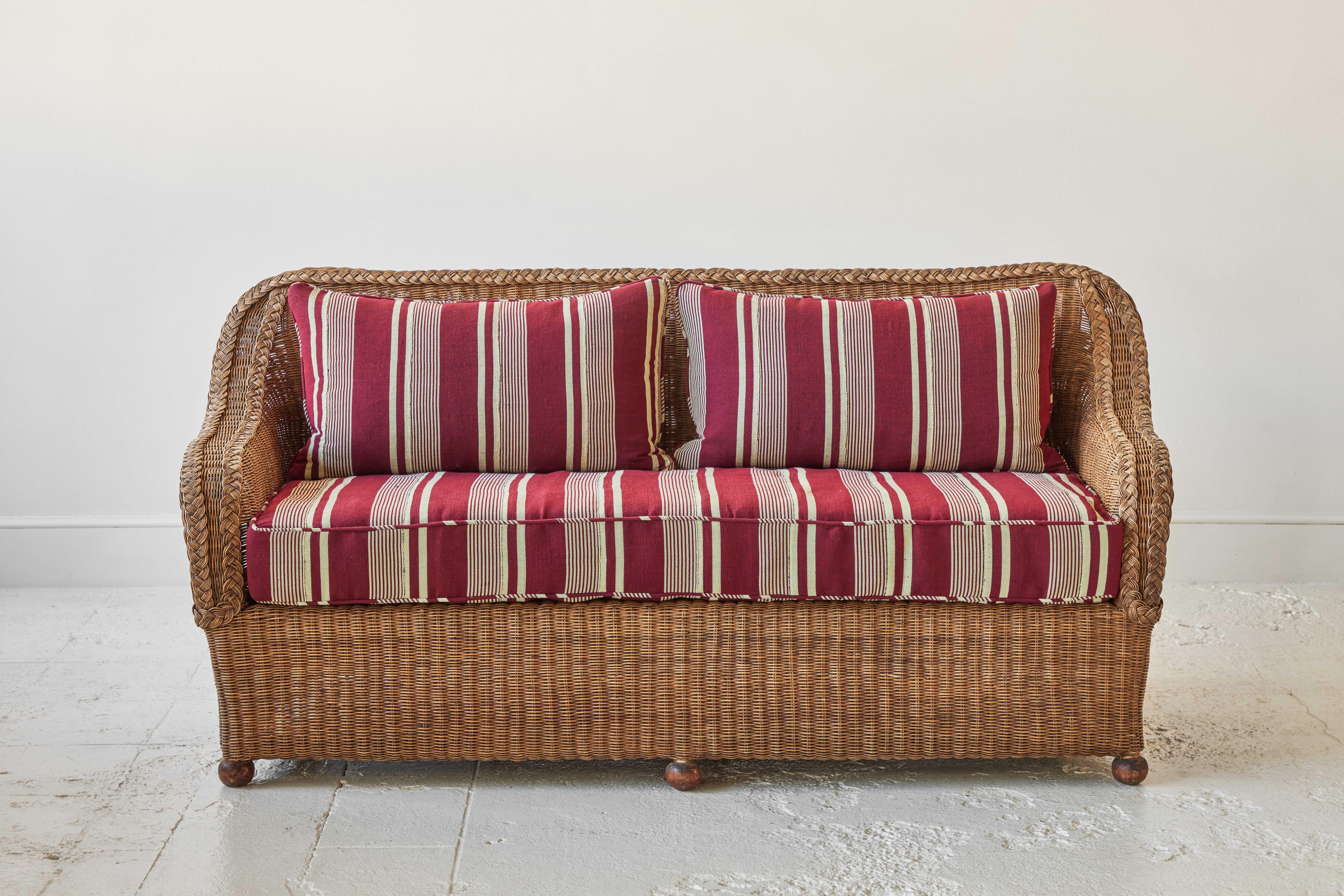 Vintage intricately detailed wicker sofa with six ball feet. The sofa has been newly upholstered in an African striped textile.