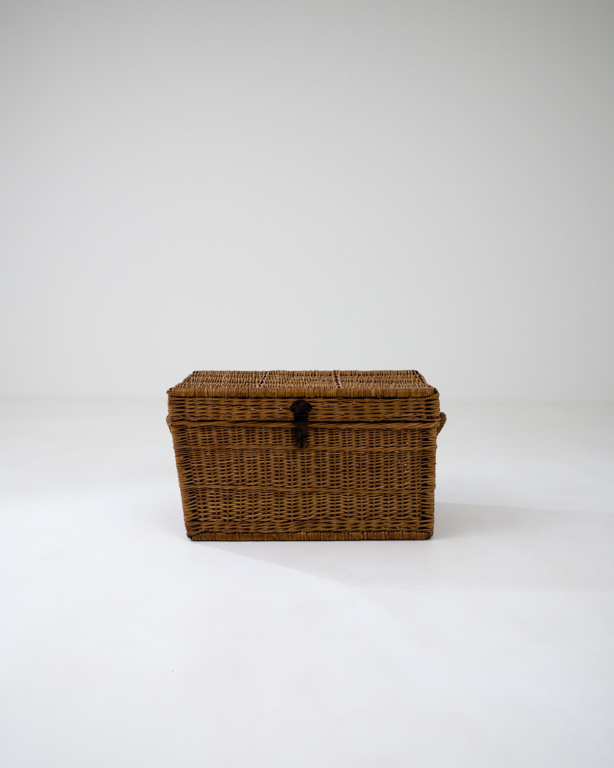 This charming and practical trunk is crafted from woven wicker, celebrated for its strength and flexibility. The intricate pattern on the rectangular base serves both an aesthetic and functional purpose, enhancing the trunk's durability. The chest