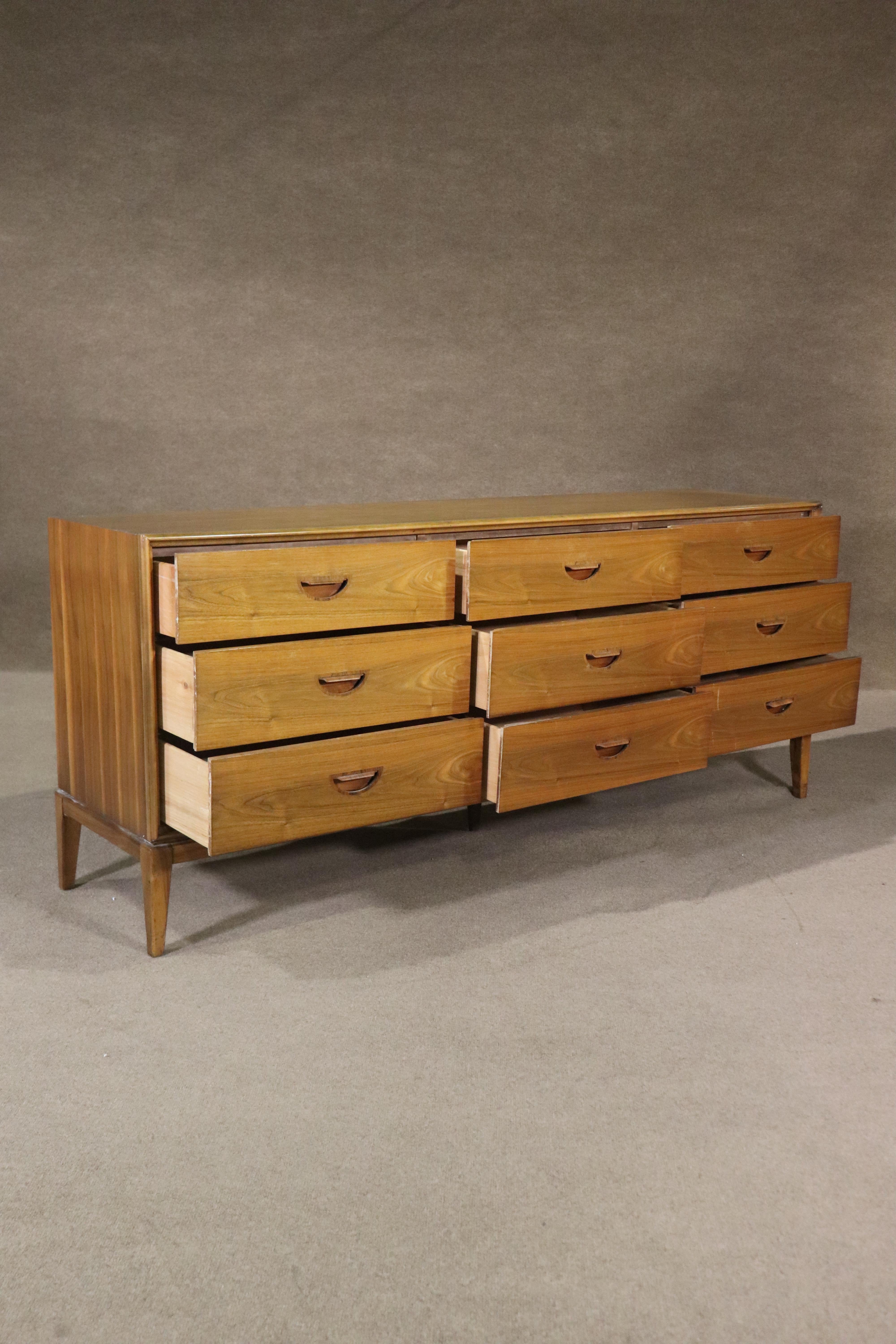 Mid-century modern long chest of drawers in stunning walnut wood grain with sculpted inset rosewood handles. Nine drawers set on tapered legs. Very simple but unique vintage design.
Please confirm location NY or NJ