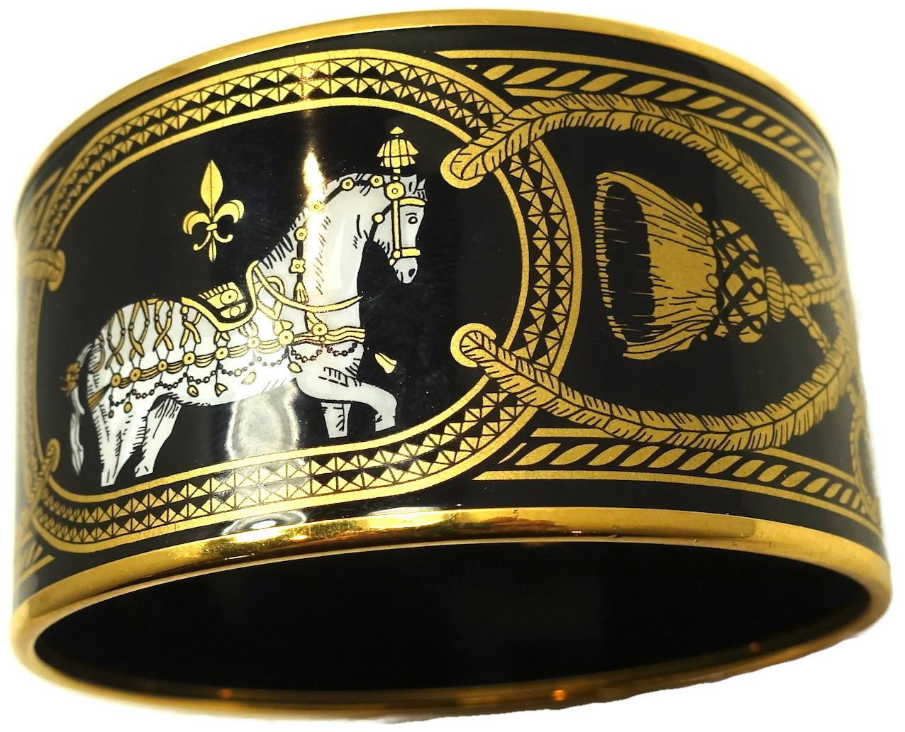 This vintage wide signed Hermes cuff bracelet has Hermes famous horse design and Fleur des Lis design on black, gold and white enameling. It has a gold tone trim.  In excellent condition, this bracelet measures 8-1/8” x 1-1/2” and is signed “Hermes