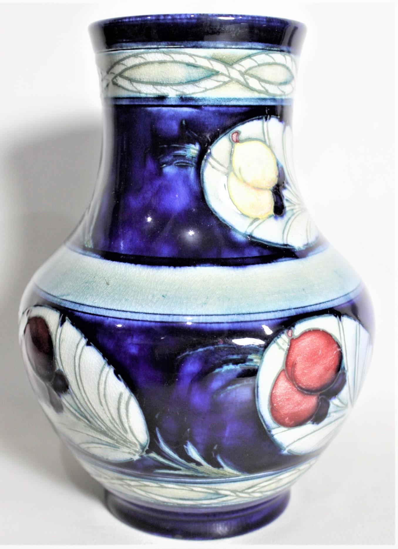 This art pottery vase was done by the Moorcroft Pottery company of England in circa 1939 using their signature deep cobalt blue ground and done in the 'Banded Wisteria' pattern. The vase is clearly signed on the base with impressed maker's marks,