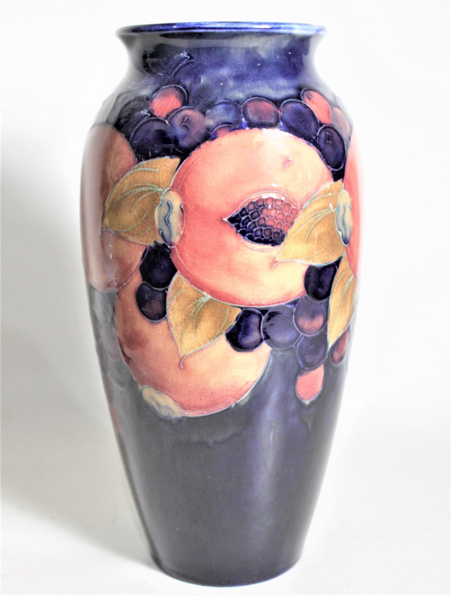 This art pottery vase was done by the Moorcroft Pottery company of England in circa 1939 using their signature deep cobalt blue ground and done in the 'Pomegranate' pattern. The vase is clearly signed on the base with impressed maker's marks, and