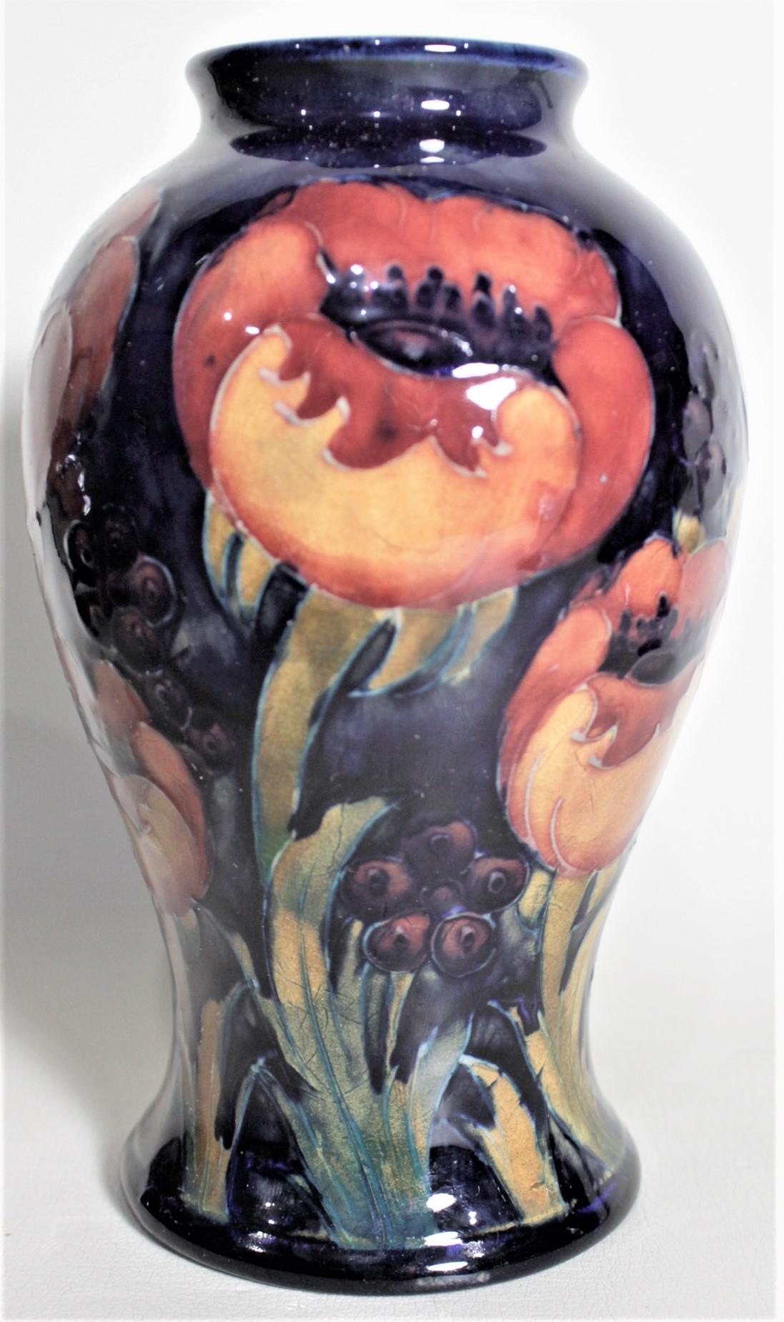 This art pottery vase was done by the Moorcroft Pottery company of England in circa 1939 using their signature deep cobalt blue ground and done in the 'Poppy' pattern. The vase is clearly signed on the base with impressed maker's marks, and hand