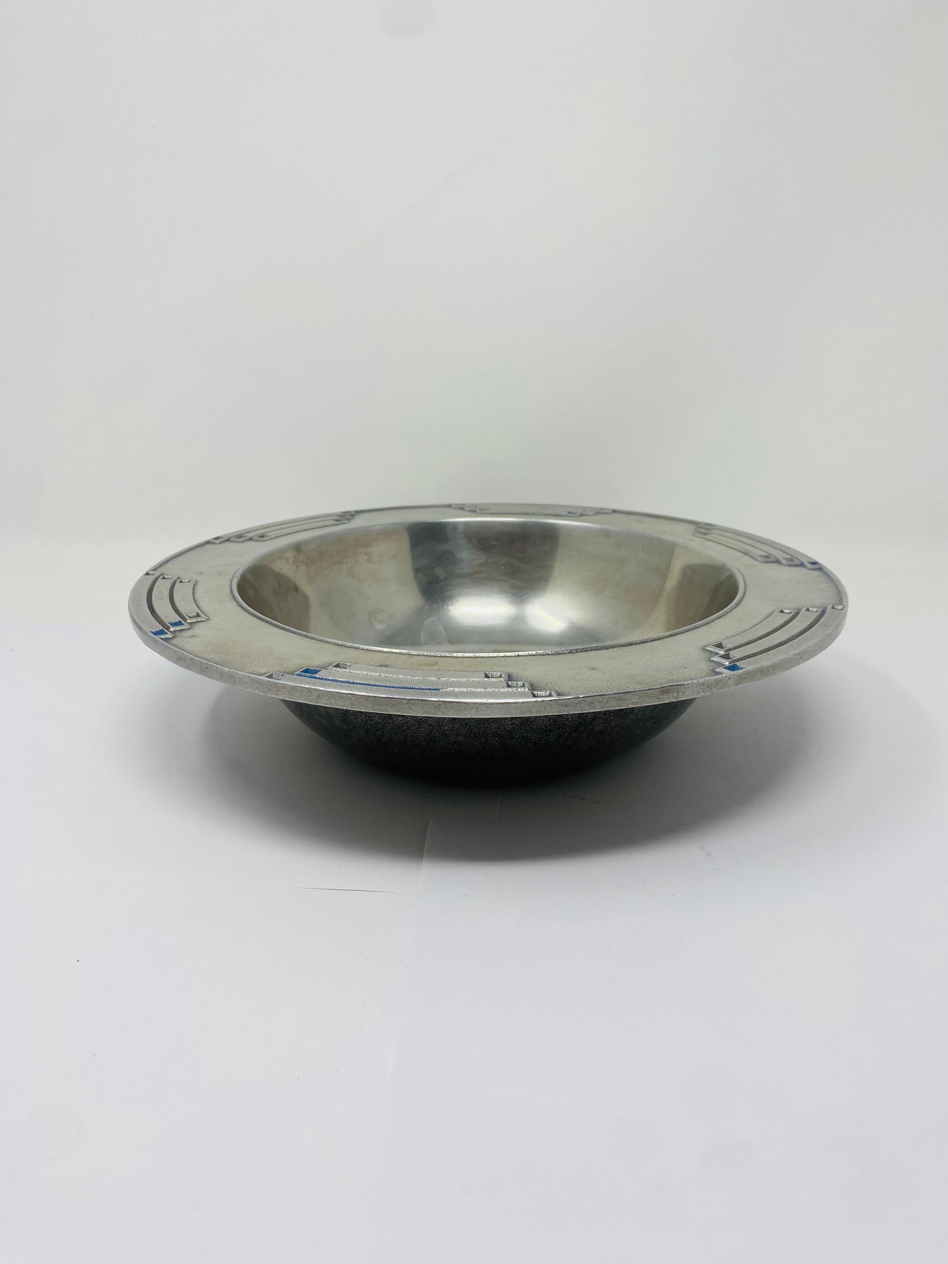 Conjunto escultórico de fuente y cuenco de peltre minimalista con profundidad de estilo.  Tanto el cuenco como la fuente presentan un diseño tribar, minimalista y elegante, que alude a elementos de diseño del suroeste e incluso a la estética art