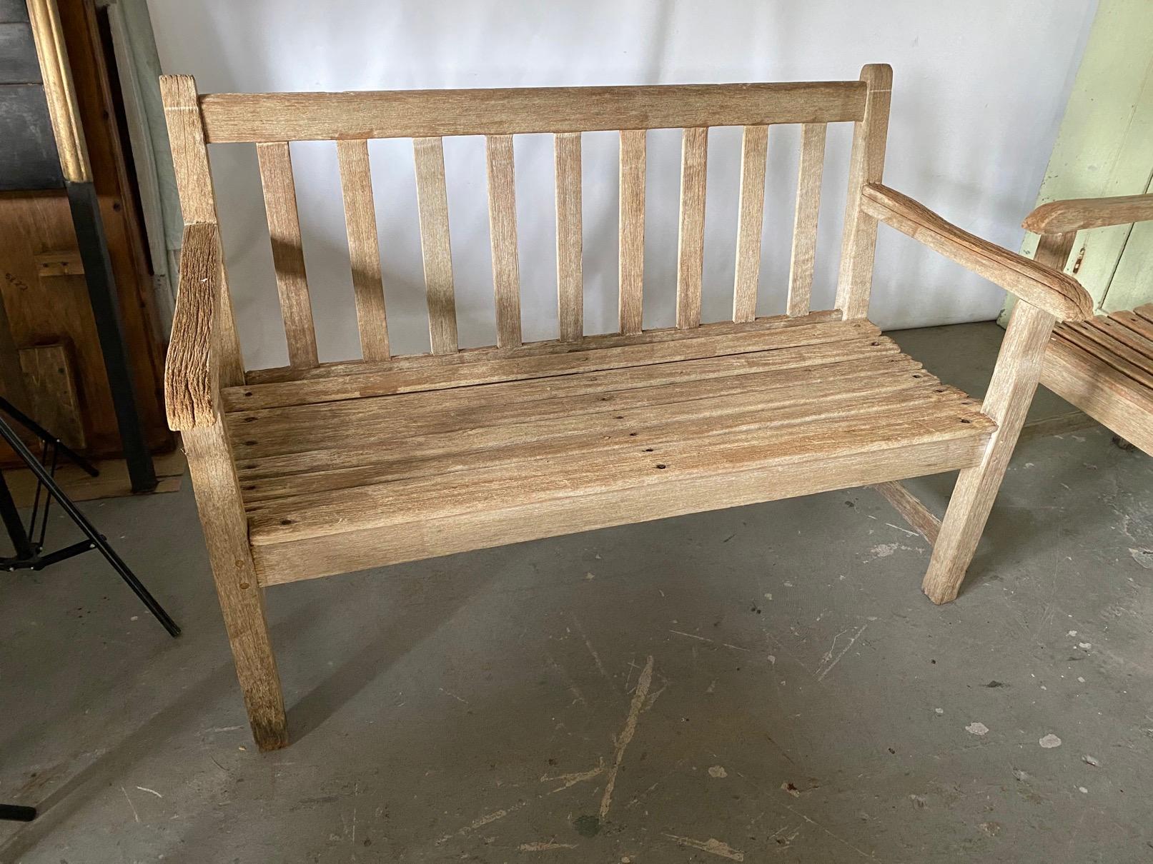 Classic styling, vintage two-seat teak bench with arms has wonderful weathered patina. A second matching bench is available. Wonderful for the patio, porch or garden.