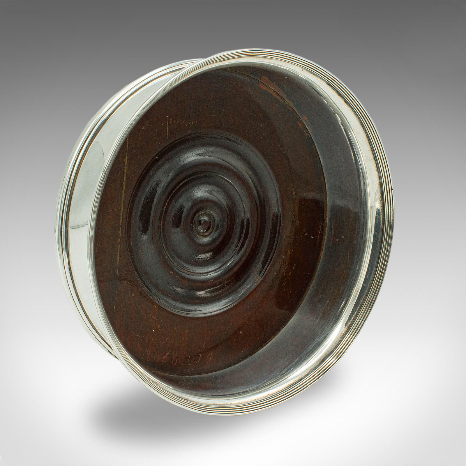 Il s'agit d'un sous-verre de bouteille de vin vintage. Porte-boissons décoratif anglais en métal argenté et en noyer, datant du début du 20e siècle, vers 1930.

Joli sous-verre du début du 20e siècle, idéal pour accueillir une bouteille de