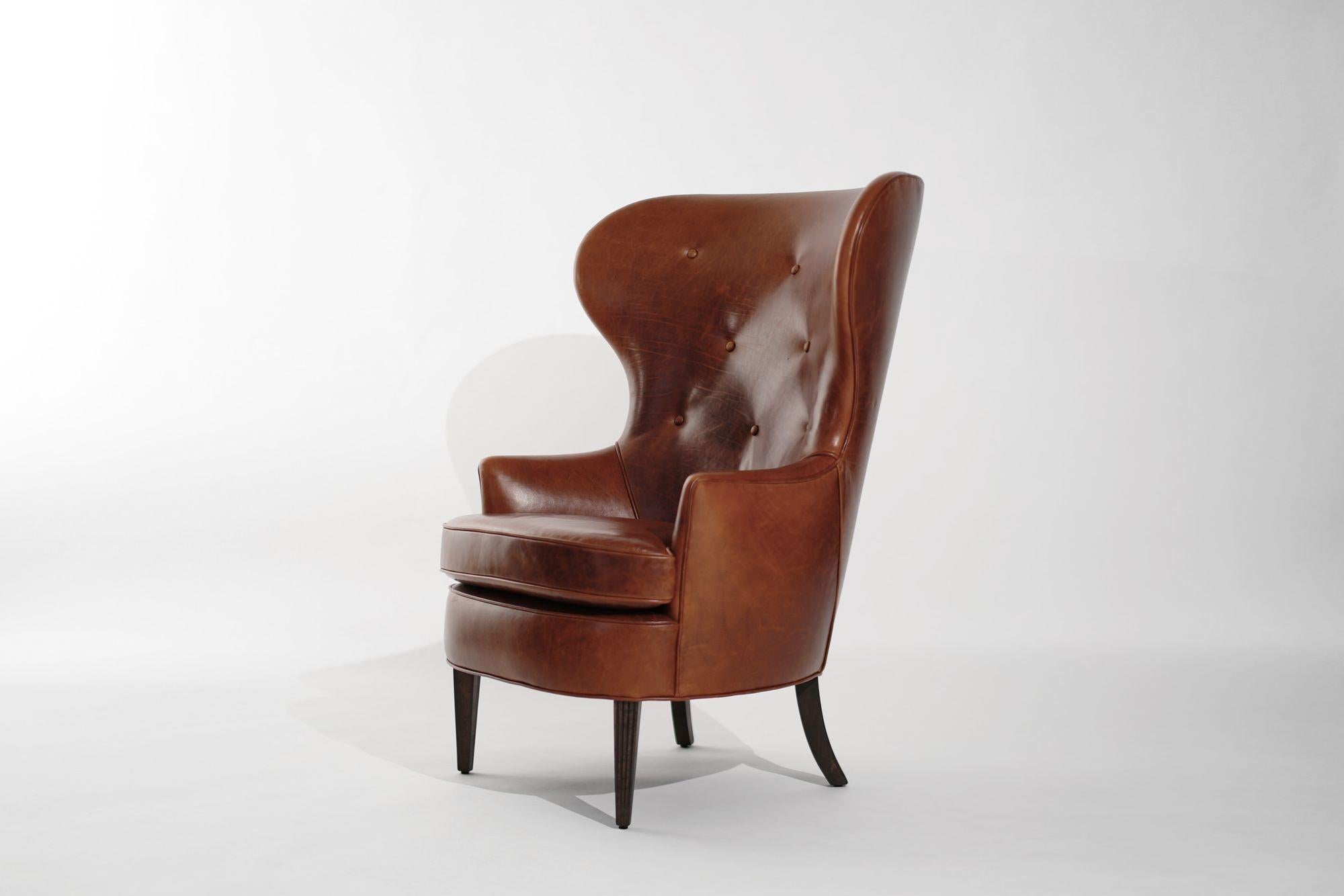Step into mid-century luxury with our meticulously restored Vintage Wingback Chair, reminiscent of Edward Wormley's iconic style for Dunbar in the 1950s. Painstakingly revived and reupholstered in sumptuous cognac leather, this classic piece exudes