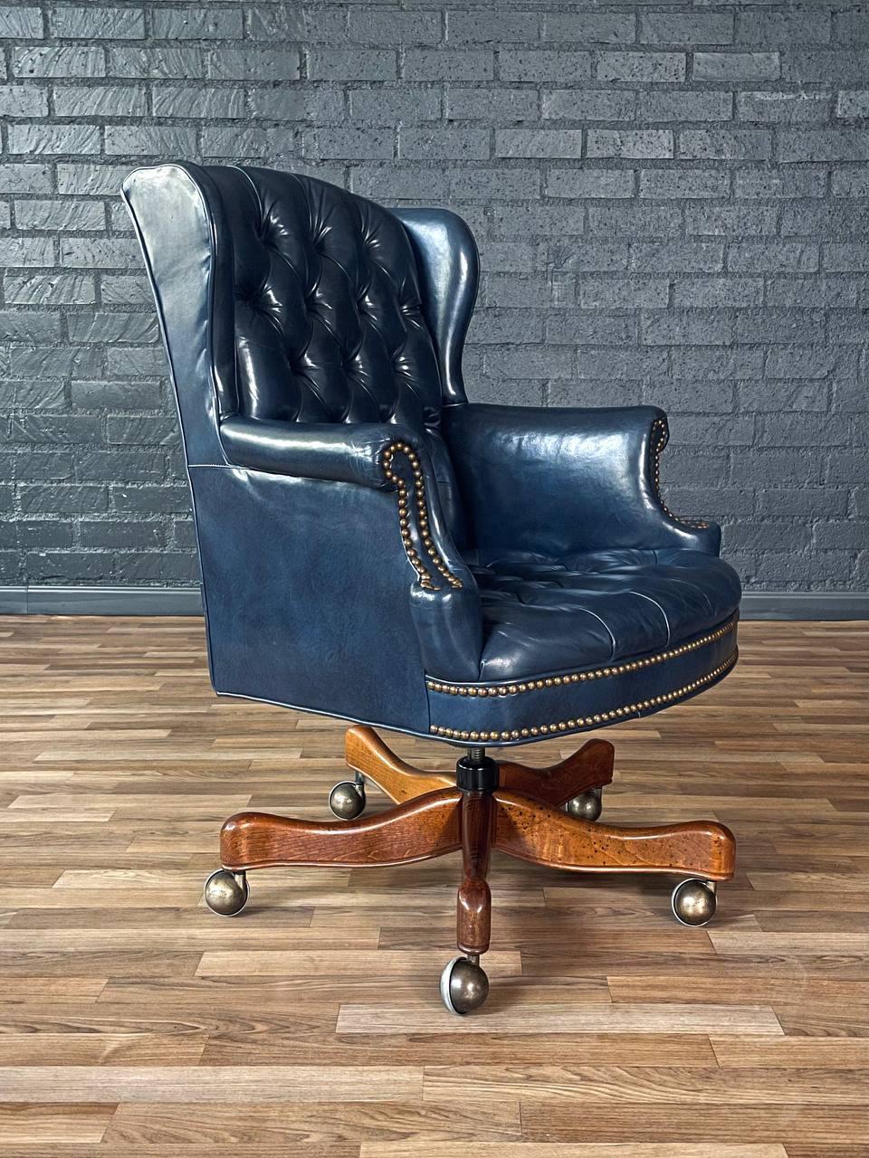 Condition: Original Vintage Condition
Materials: Blue Leather, Walnut-Stained Maple, Brass Nailhead Trim
Style: English Chesterfield  

This vintage English Chesterfield-style office chair from the 1960s features rich blue leather upholstery with