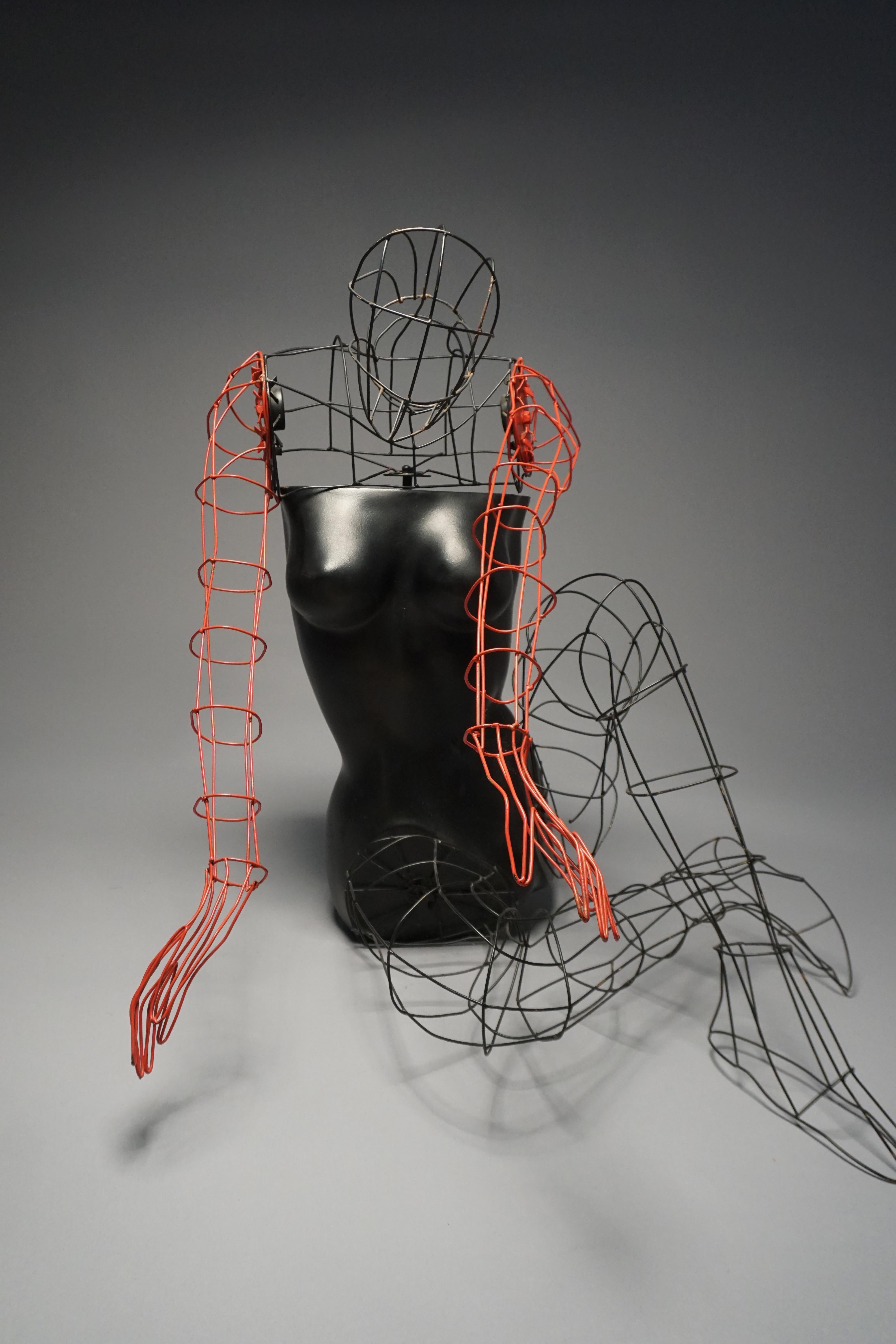 A wonderful, rare store display mannequin, circa 1970s, features a composite torso finished in smooth black paint. The torso is accompanied by wire arms, legs, and head, with the arms and hands painted in vivid red, while the head and legs retain a