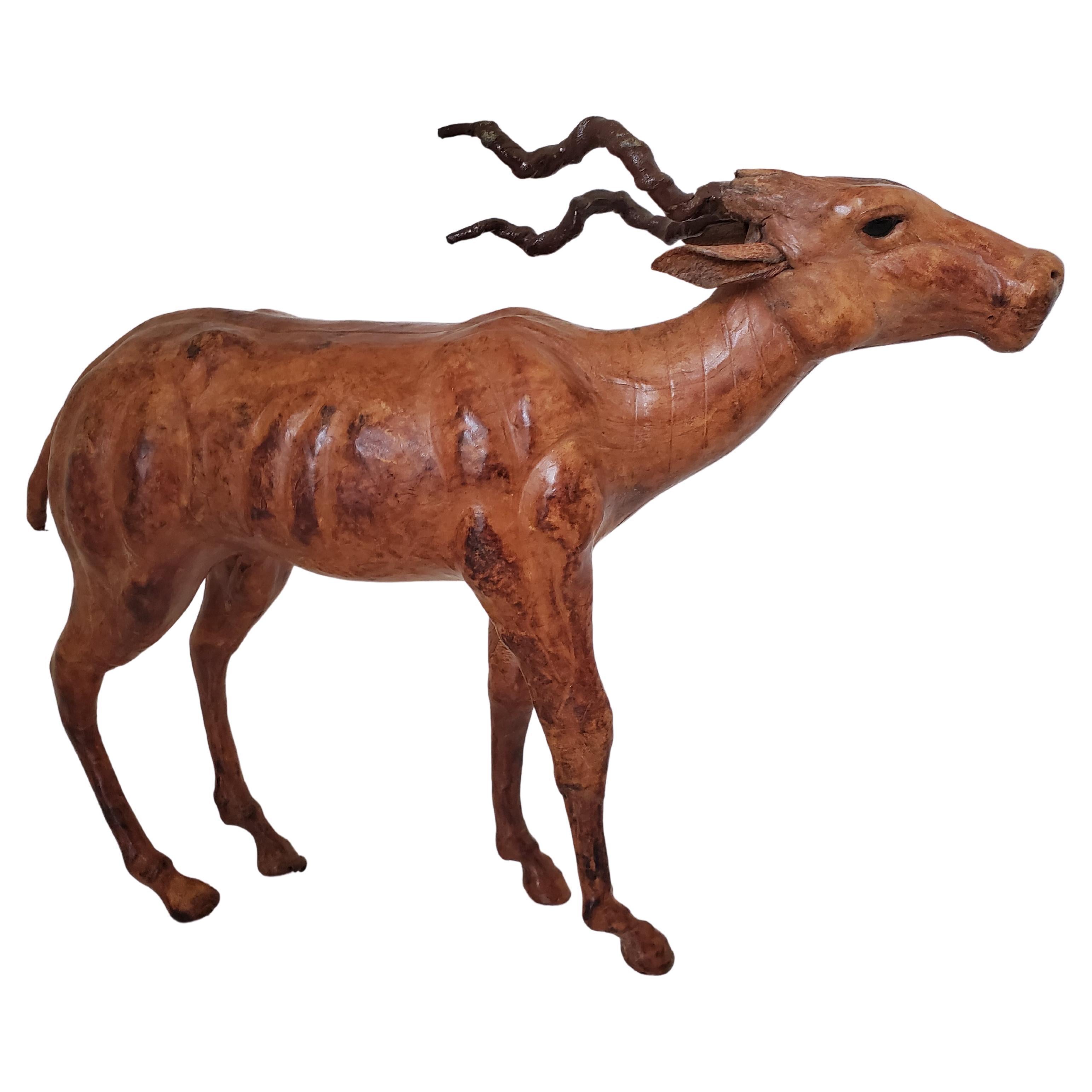 This vintage wood and leather animal sculpture from the early 20th century is likely from Liberty's London. This sculpture, hand carved in wood and clad in leather, depicts a lifelike gazelle that exudes grace in form, stance, and proportion. The
