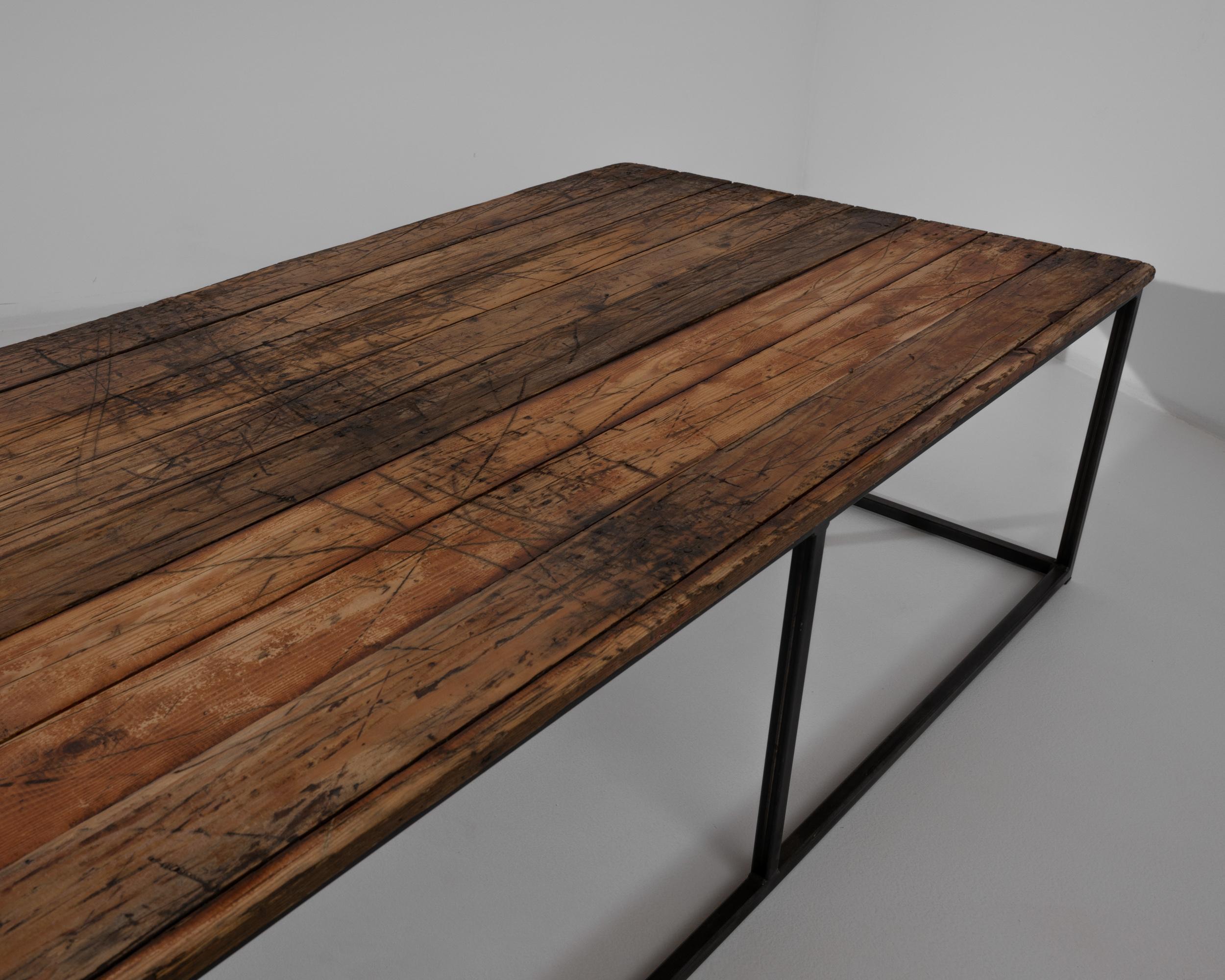 Wooden planks from France, circa 1950, rest on a steel base. Blending sleek and rustic, this 18” tall coffee table makes a comfortable and stylish place to rest your drink. Simple symmetry sings in this handcrafted table featuring a minimal metal