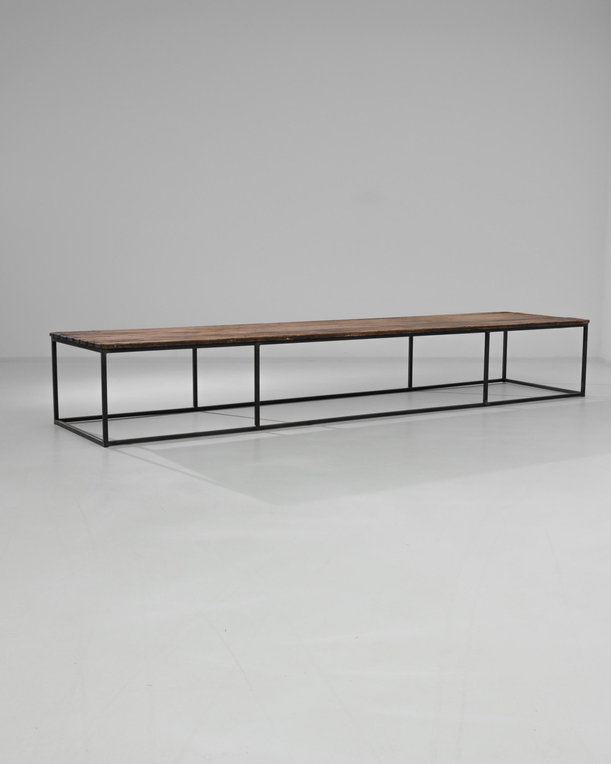 Wooden planks from France, circa 1950, rest on a steel base. Blending sleek and rustic, this 18” tall coffee table makes a comfortable and stylish place to rest your drink. Simple symmetry sings in this handcrafted table featuring a minimal metal